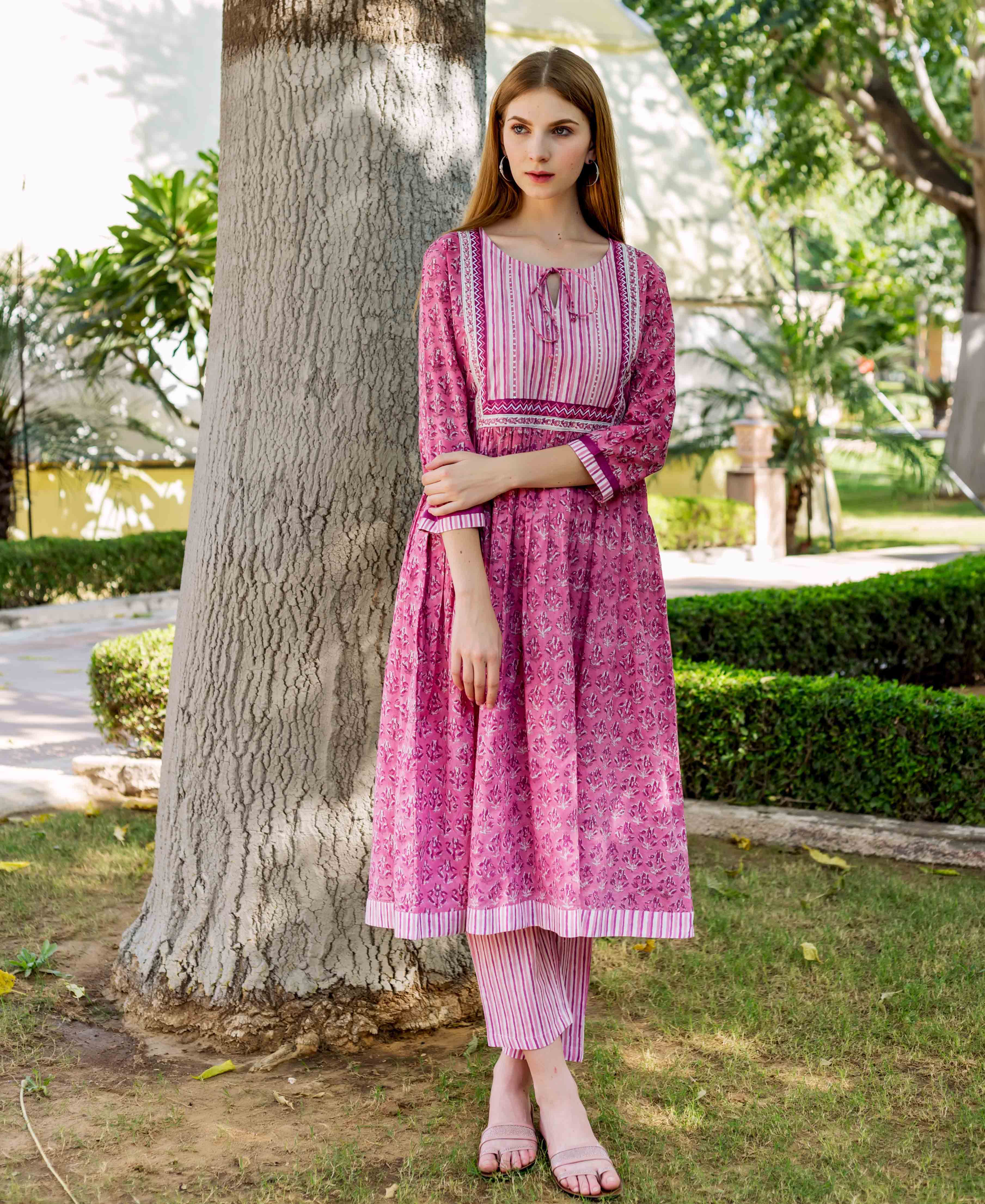 Front view model wearing pink hand-block-printed A-line kurta with striped yoke and pants.