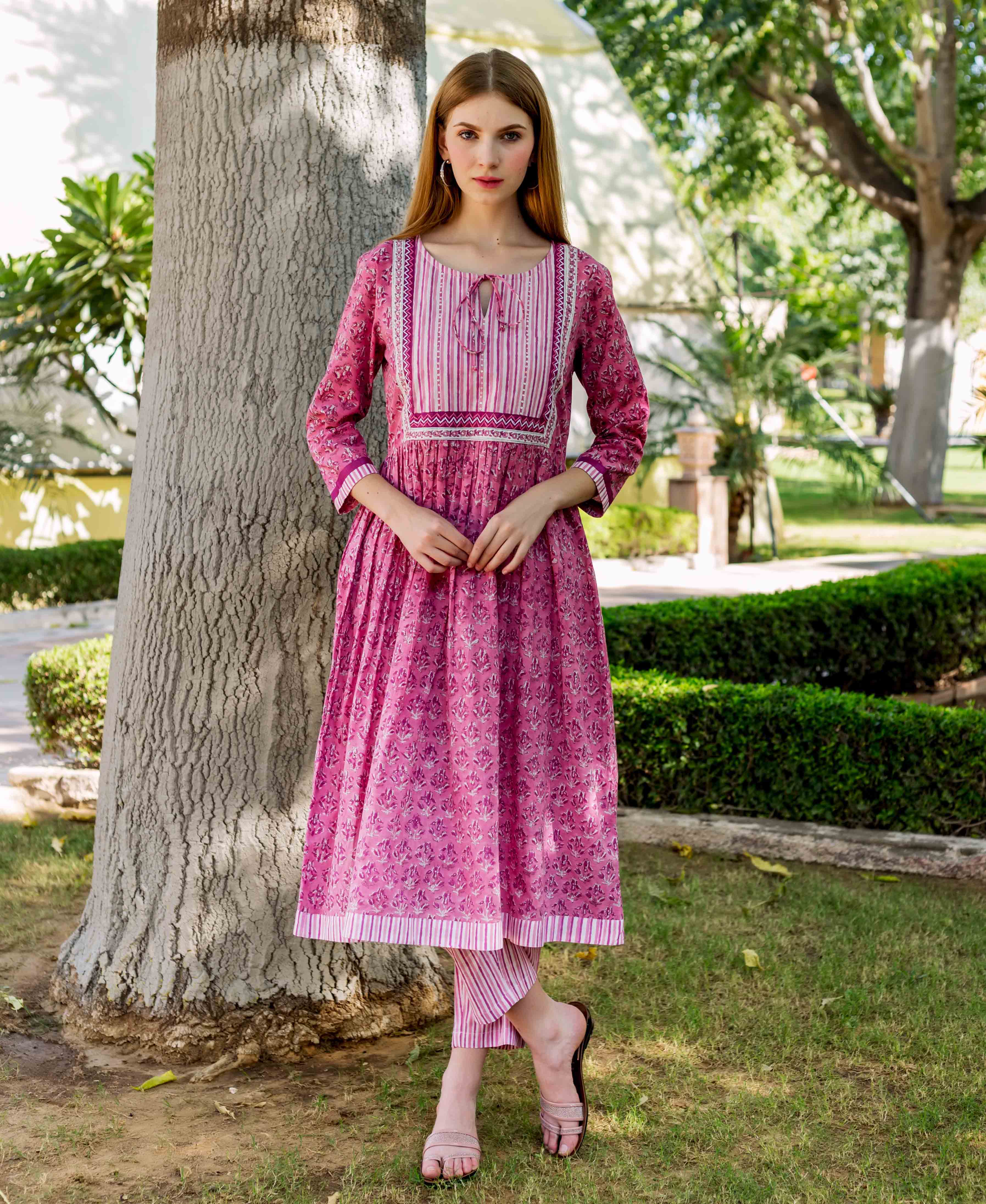 A model wearing a pink, hand-block-printed A-line kurta with a floral pattern.