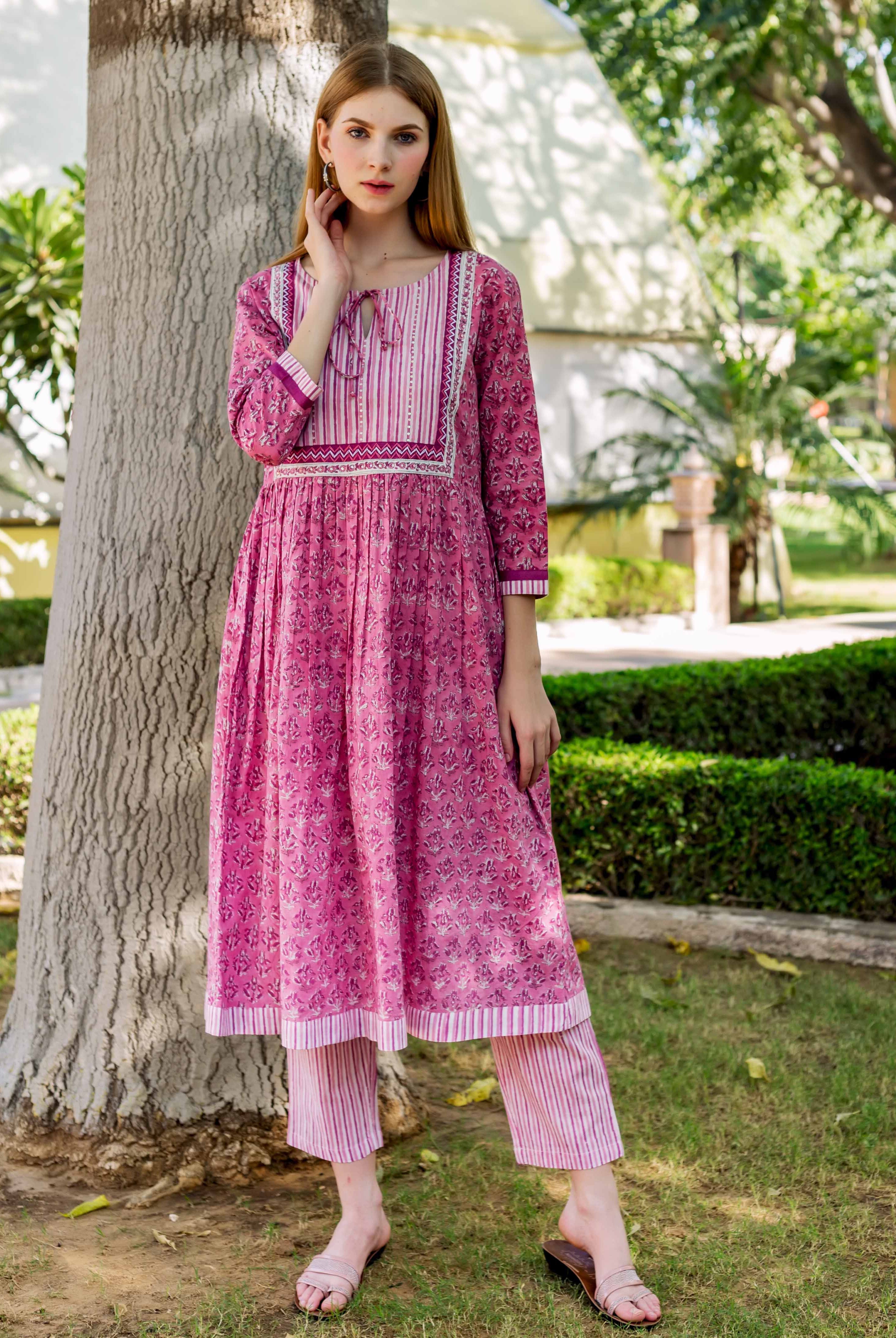 Full shot of model in pink A-line cotton kurta with floral block print and striped pants.