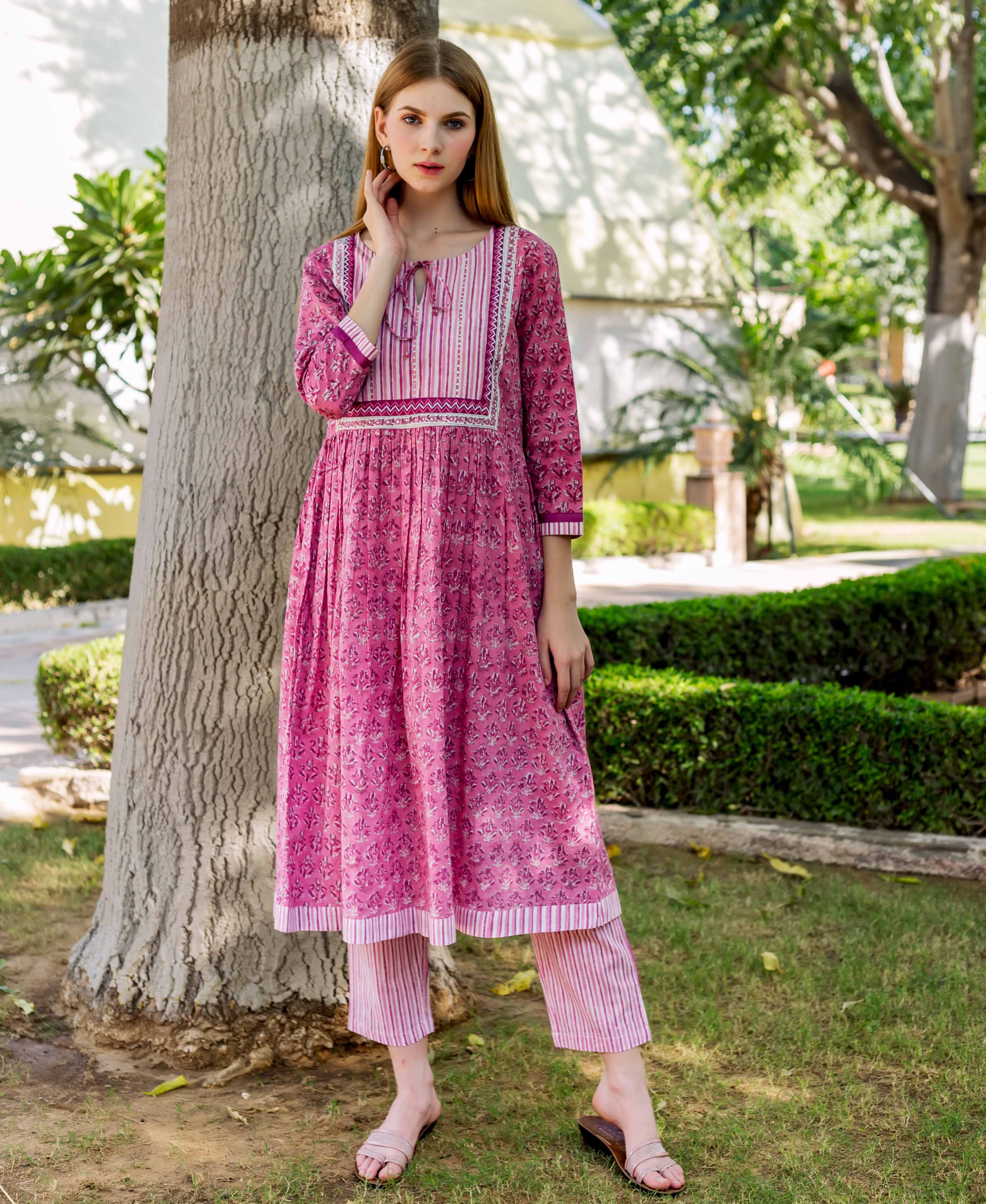 Full shot of model in pink A-line cotton kurta with floral block print and striped pants.