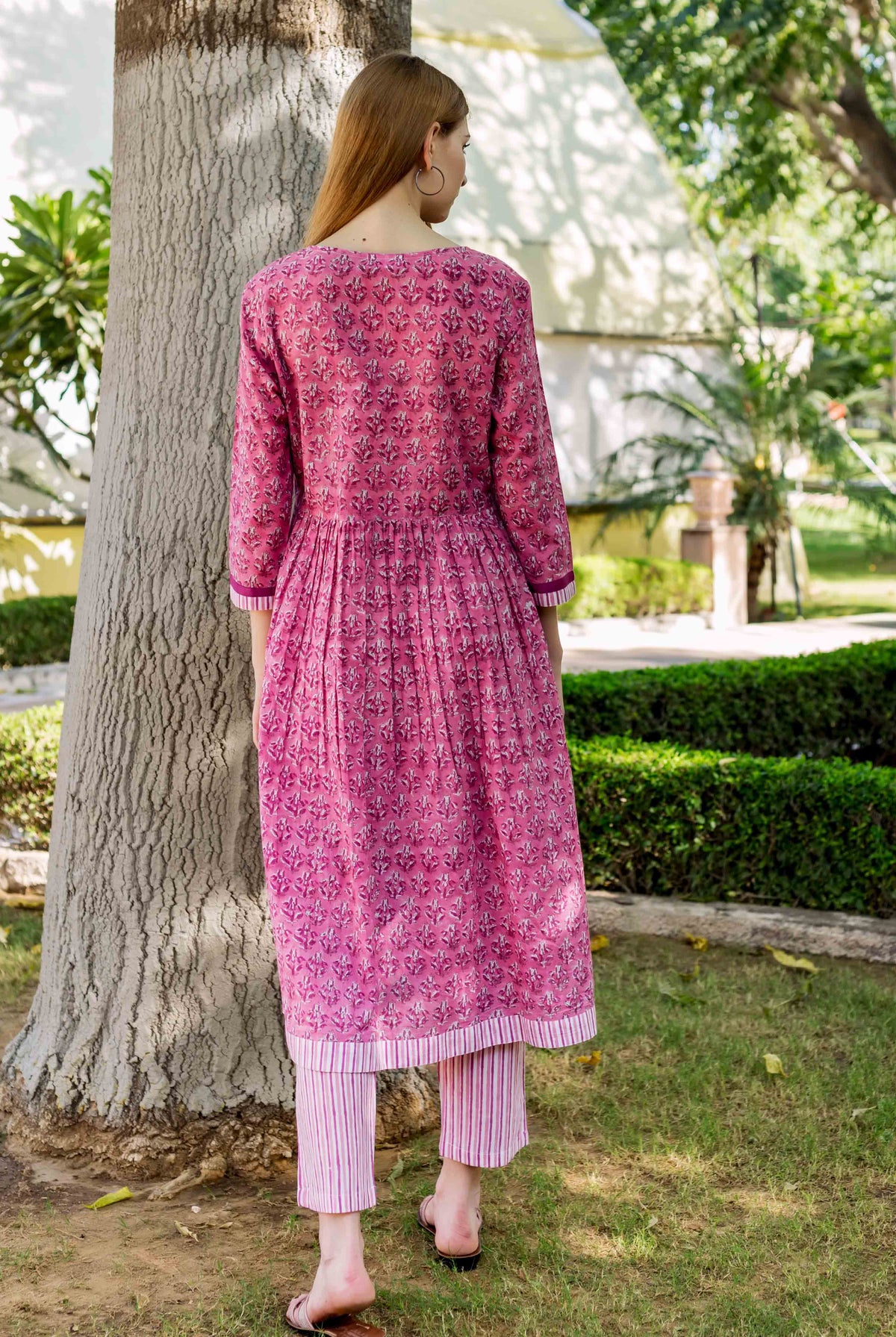 A model wearing a pink, floral-printed, A-line kurta with vertical stripes on the bottom.