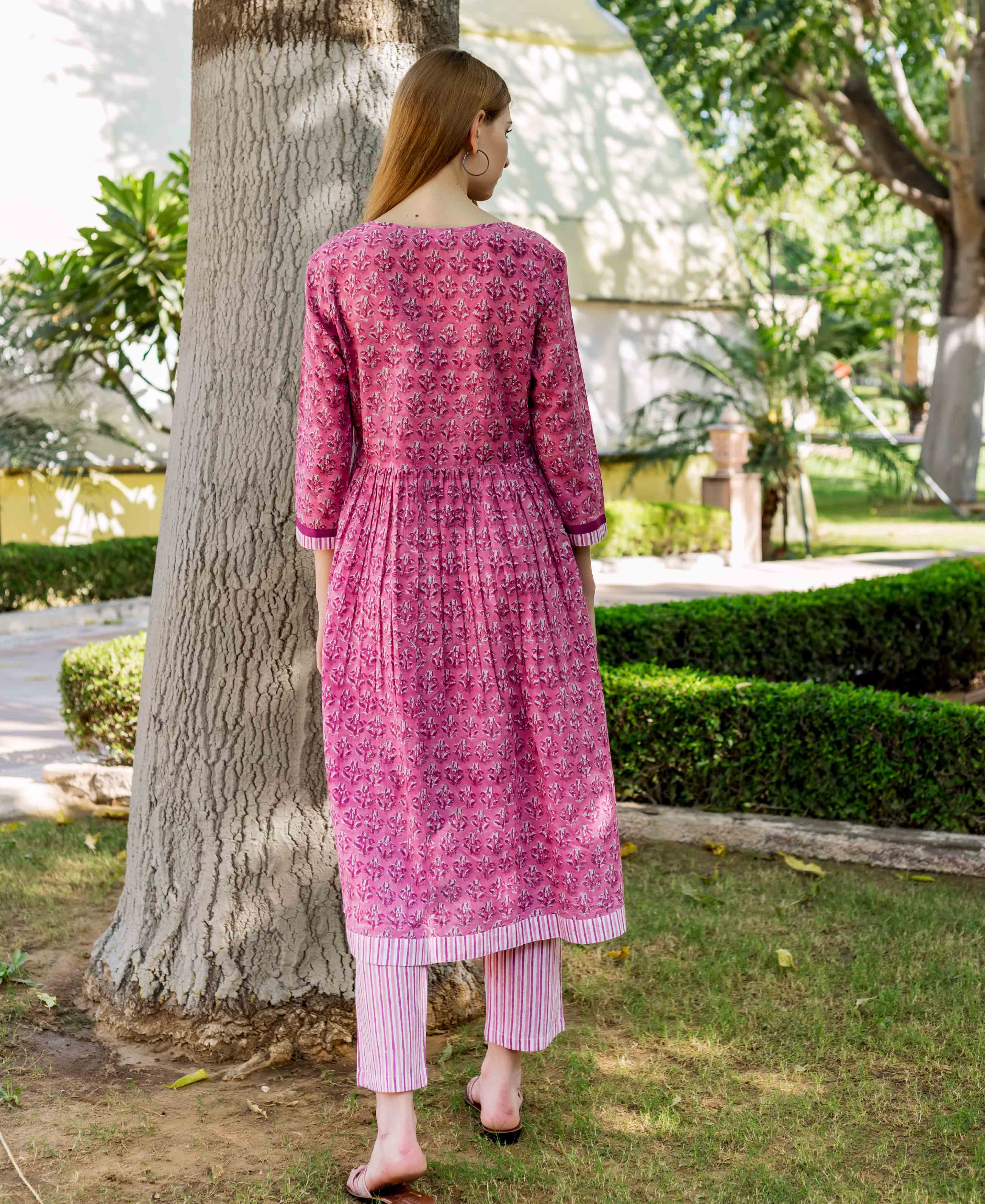 A model wearing a pink, floral-printed, A-line kurta with vertical stripes on the bottom.
