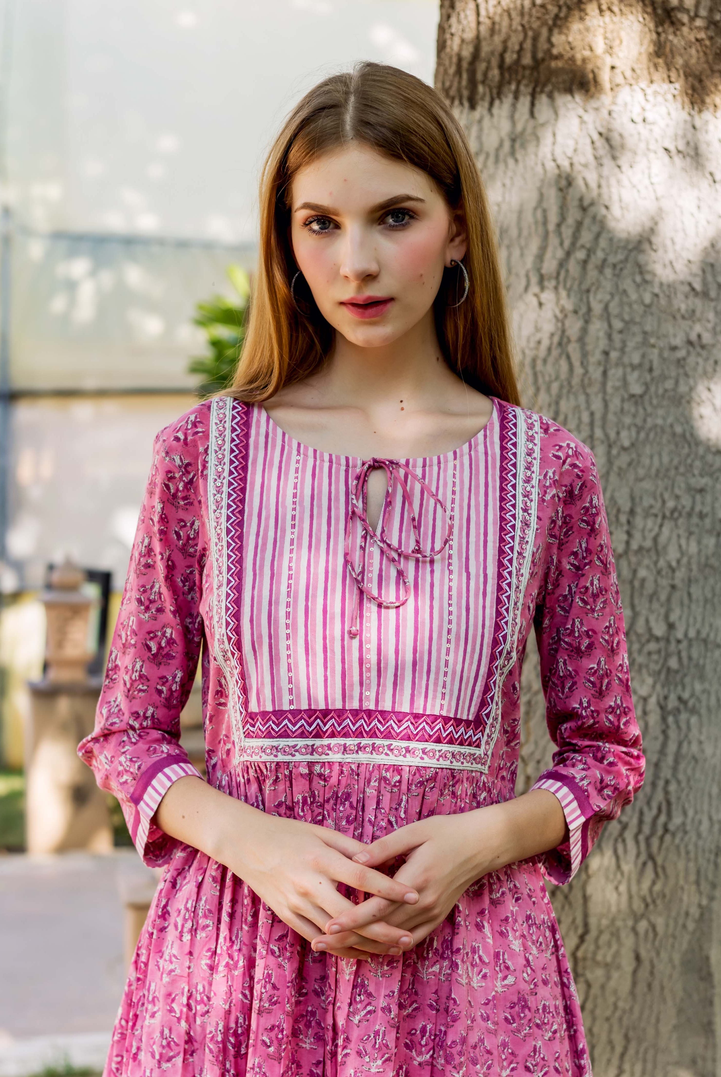 Pink hand-block printed cotton kurta on model, featuring floral body and striped yoke.