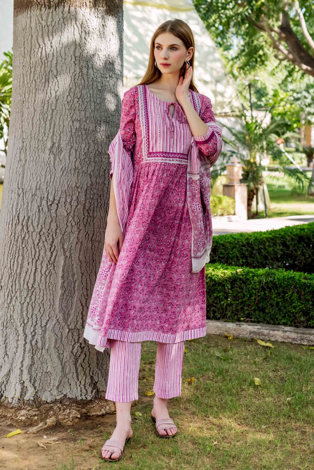 Front view model in pink floral hand-block-printed A-line kurta with striped pants and dupatta.