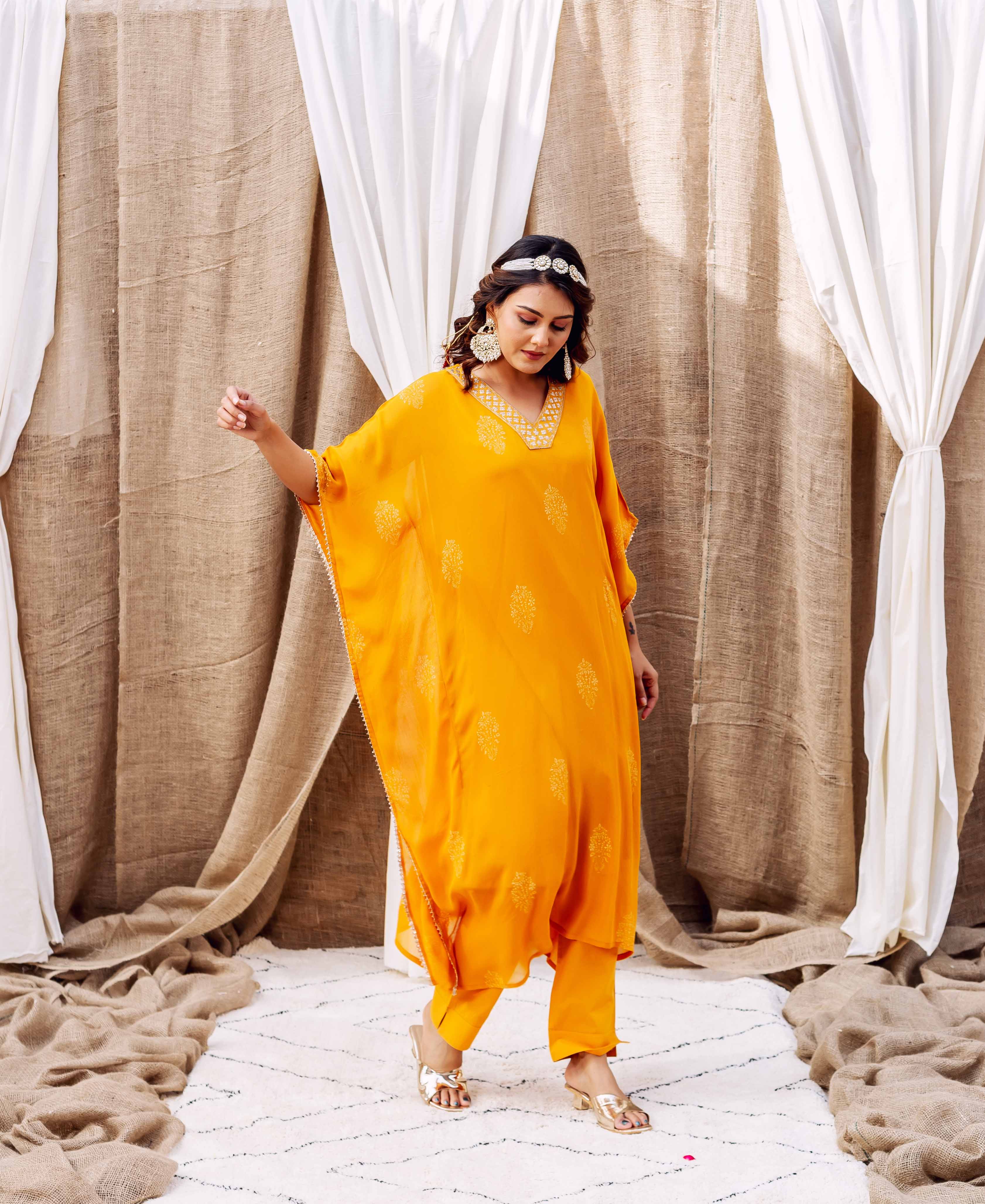Model wearing a vibrant yellow kaftan set with subtle gold hand-block-printed patterns, full shot.