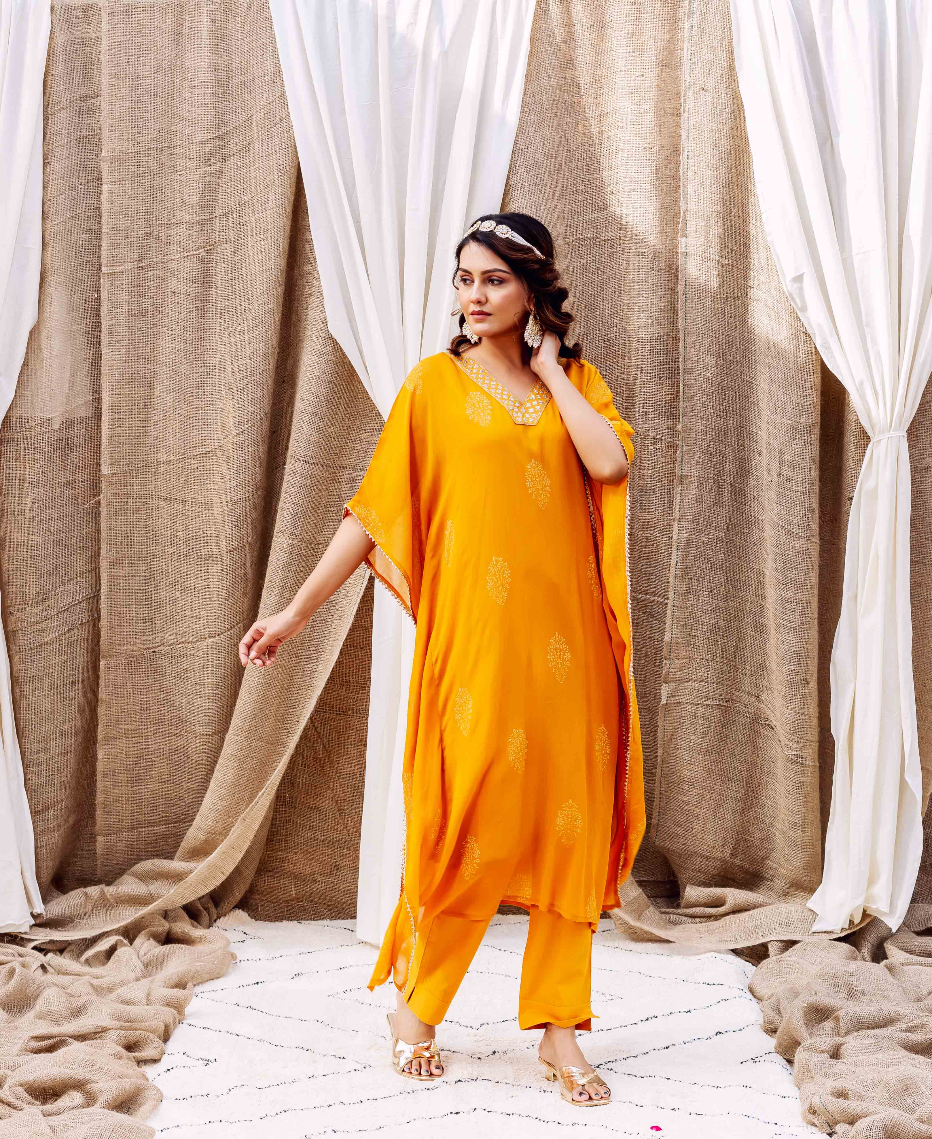 Model standing in a vibrant yellow kaftan set with delicate golden patterns.