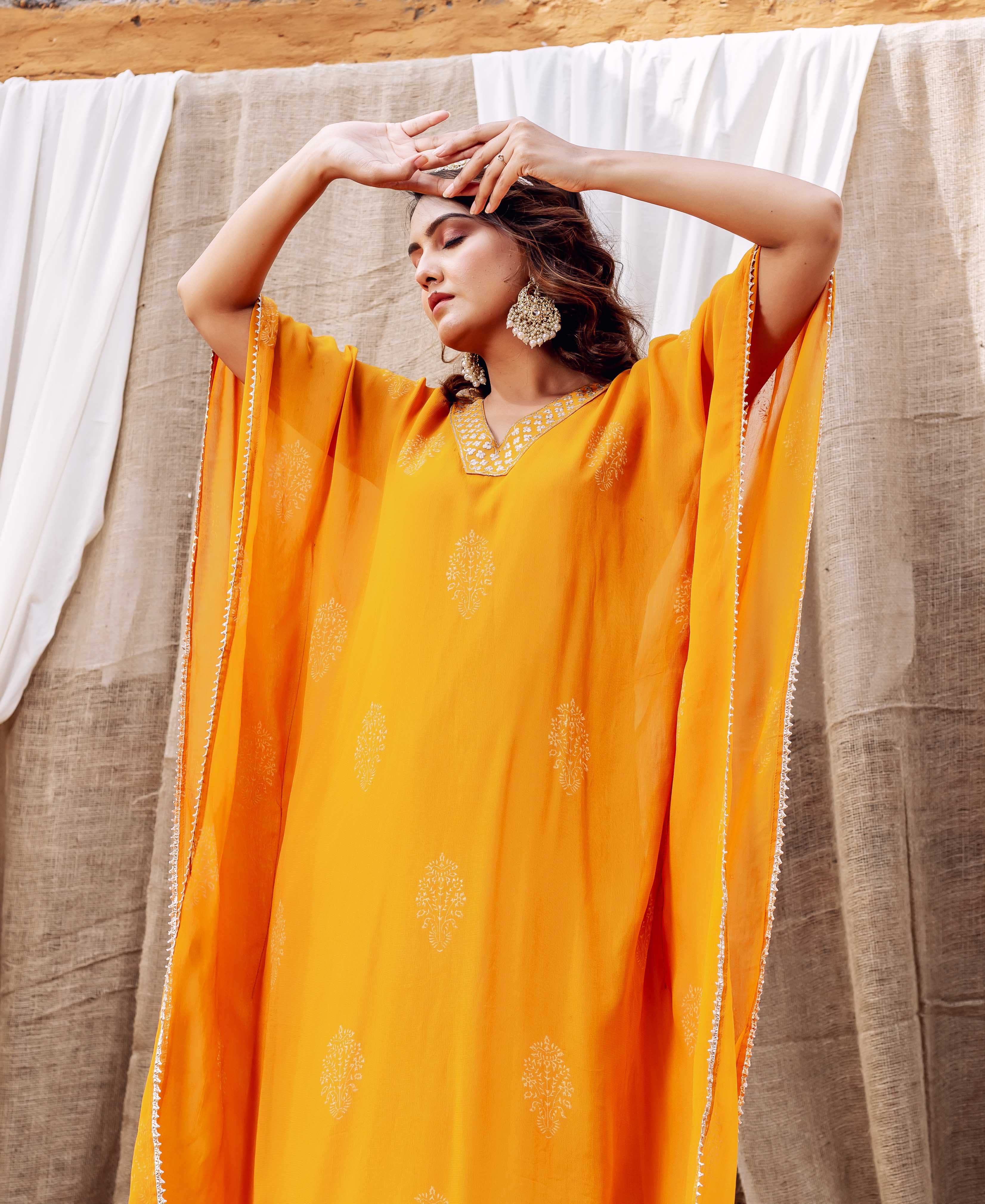 Model in a vibrant yellow embroidered kaftan featuring white motifs and delicate silver trim.
