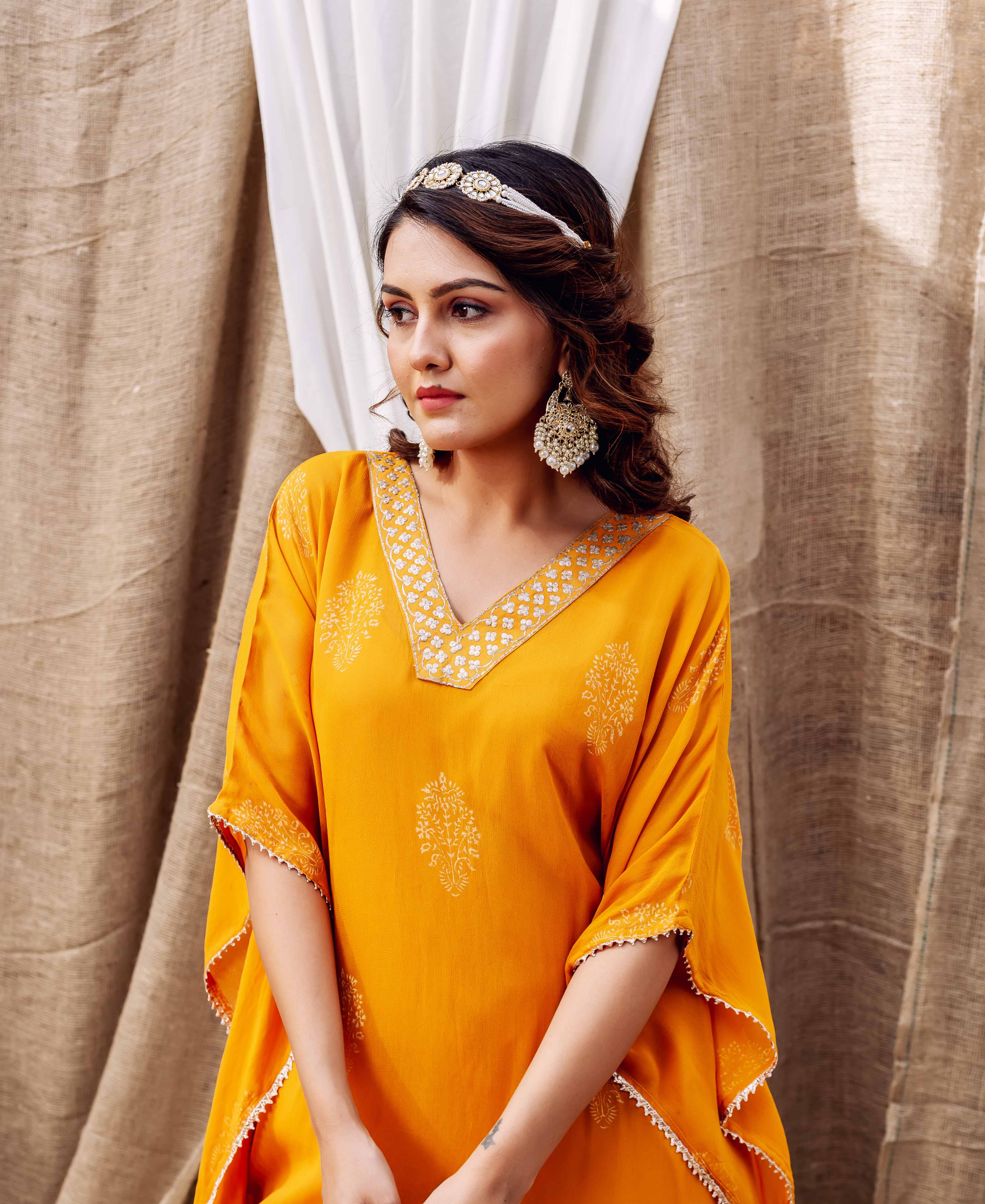 Yellow hand-block-printed kaftan with embroidered V-neck on model looking away.