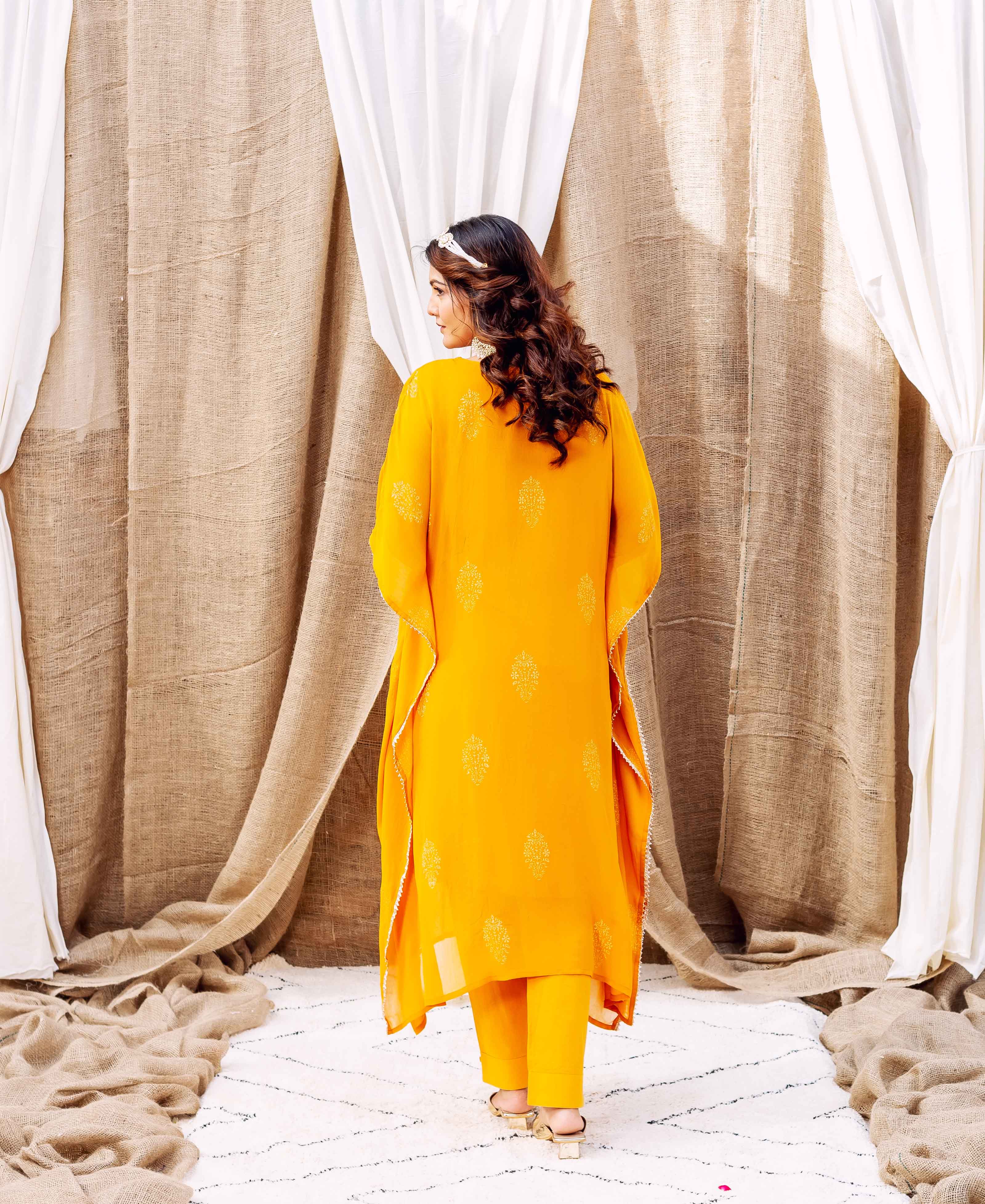 Rear view of model in a vibrant yellow kaftan set with delicate gold patterns.