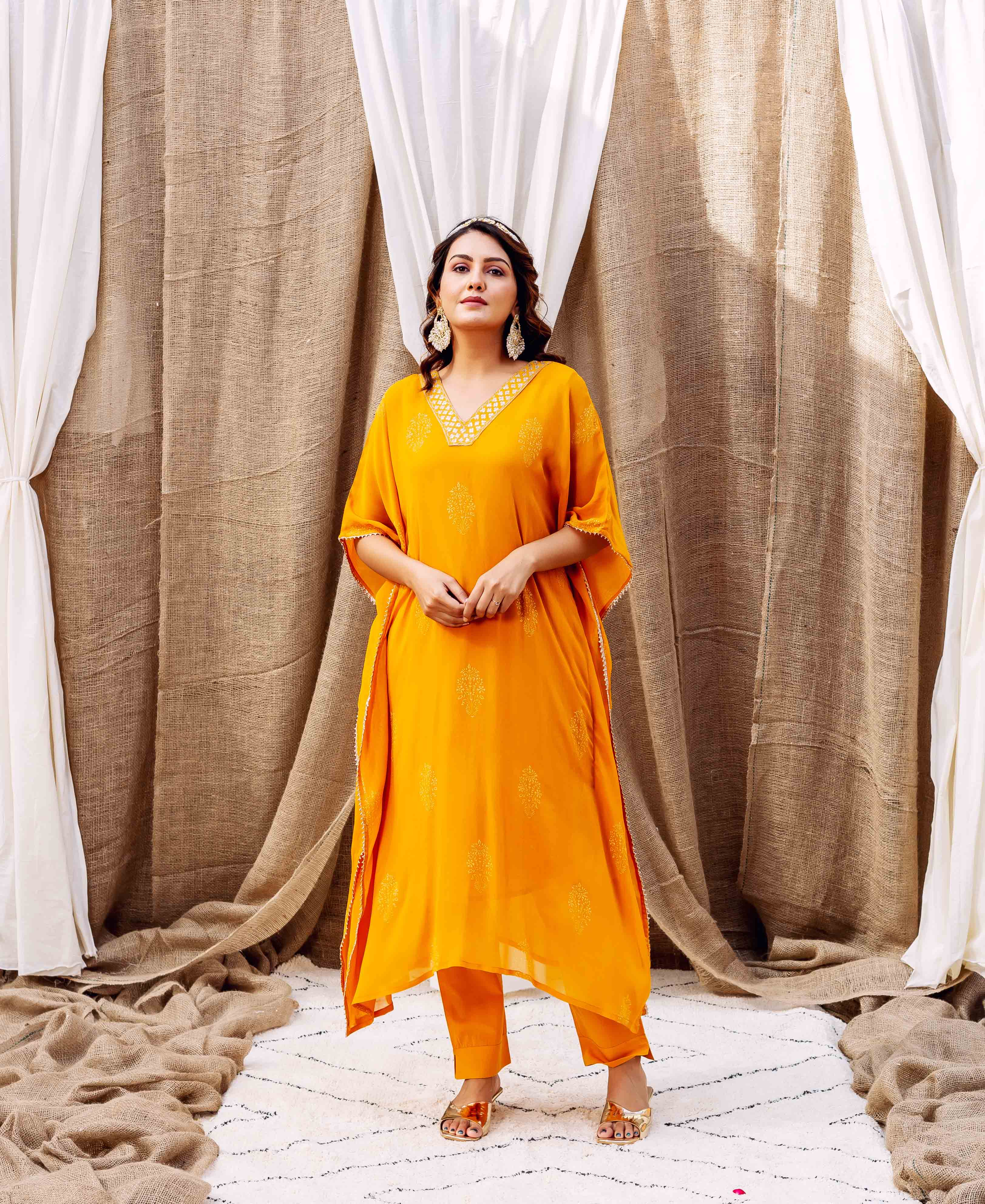 Full-length model in a vibrant yellow embroidered kaftan set with ethnic block print.