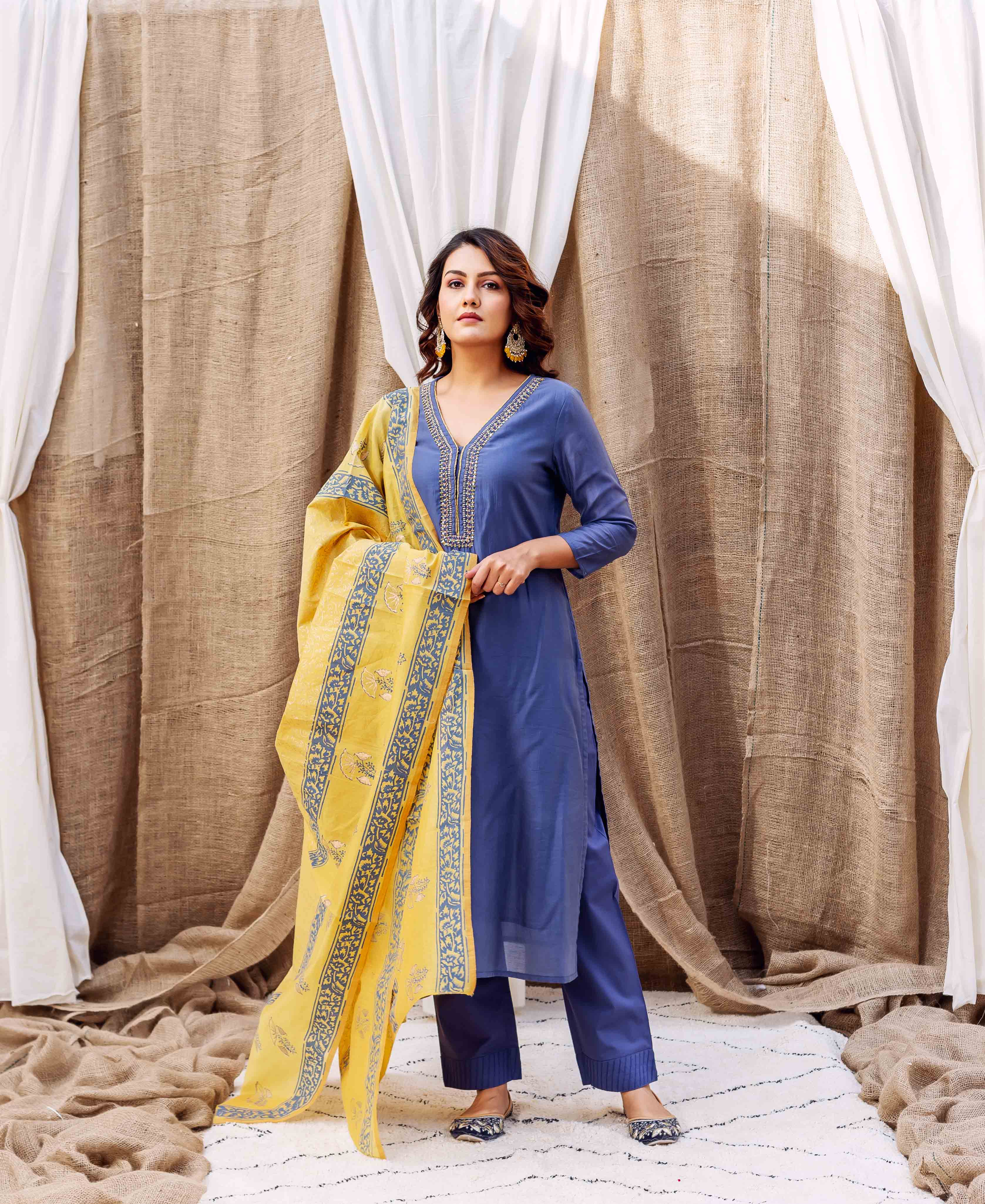 Model wears steel blue kurta set with embroidered neck and yellow block-printed dupatta.