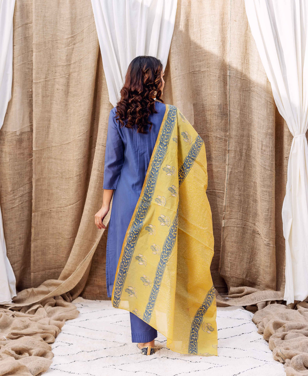 Back view of model in steel blue kurta with yellow hand-block printed dupatta.