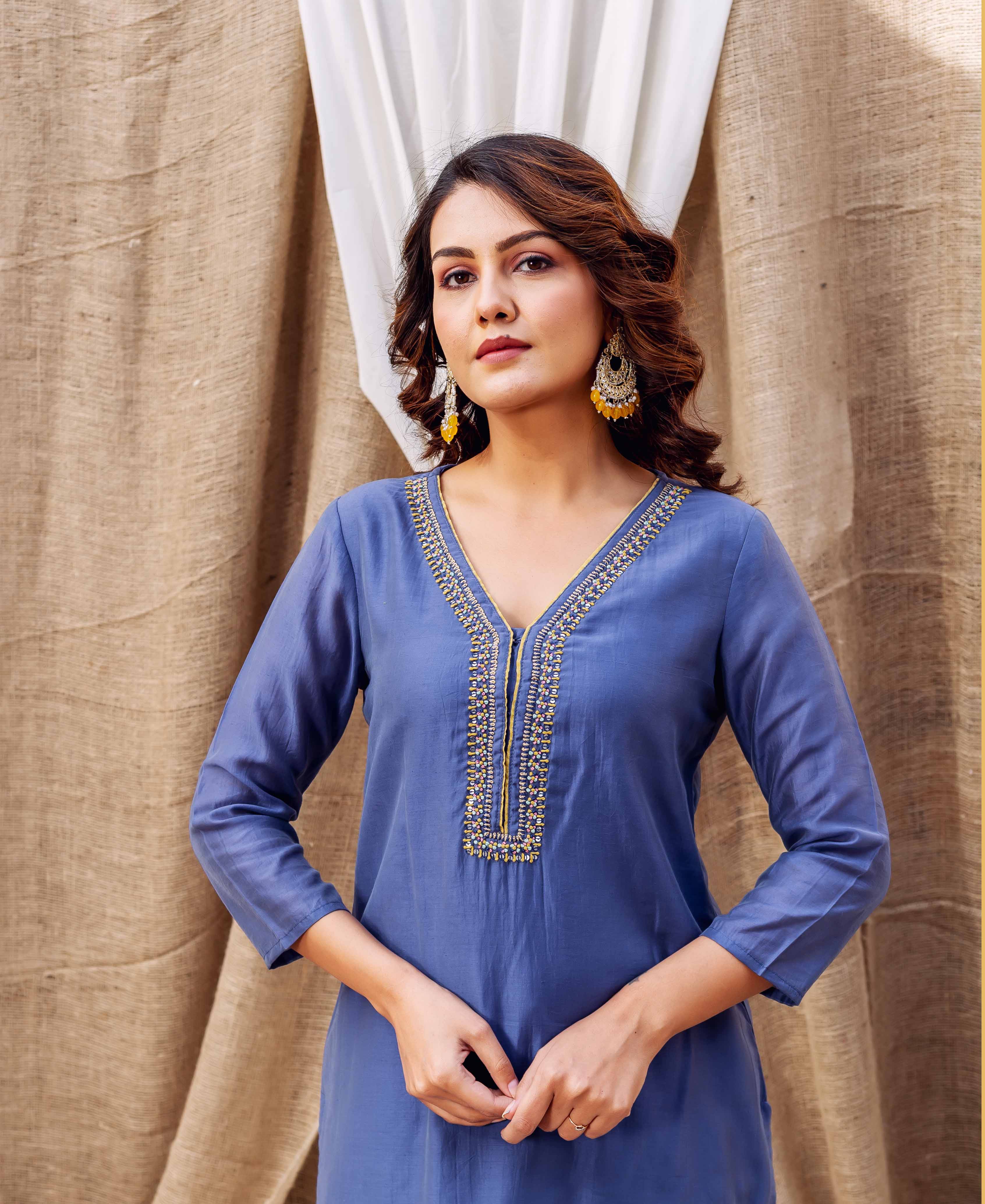 A woman in a steel blue kurta with gold embroidery.