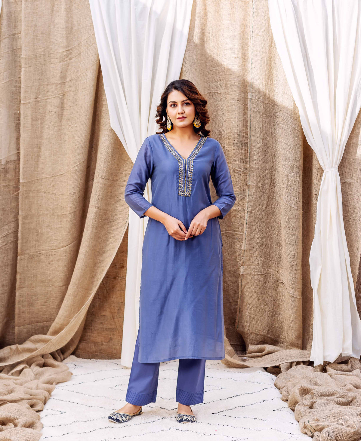 A woman in a steel blue kurta with gold embroidery and block print.