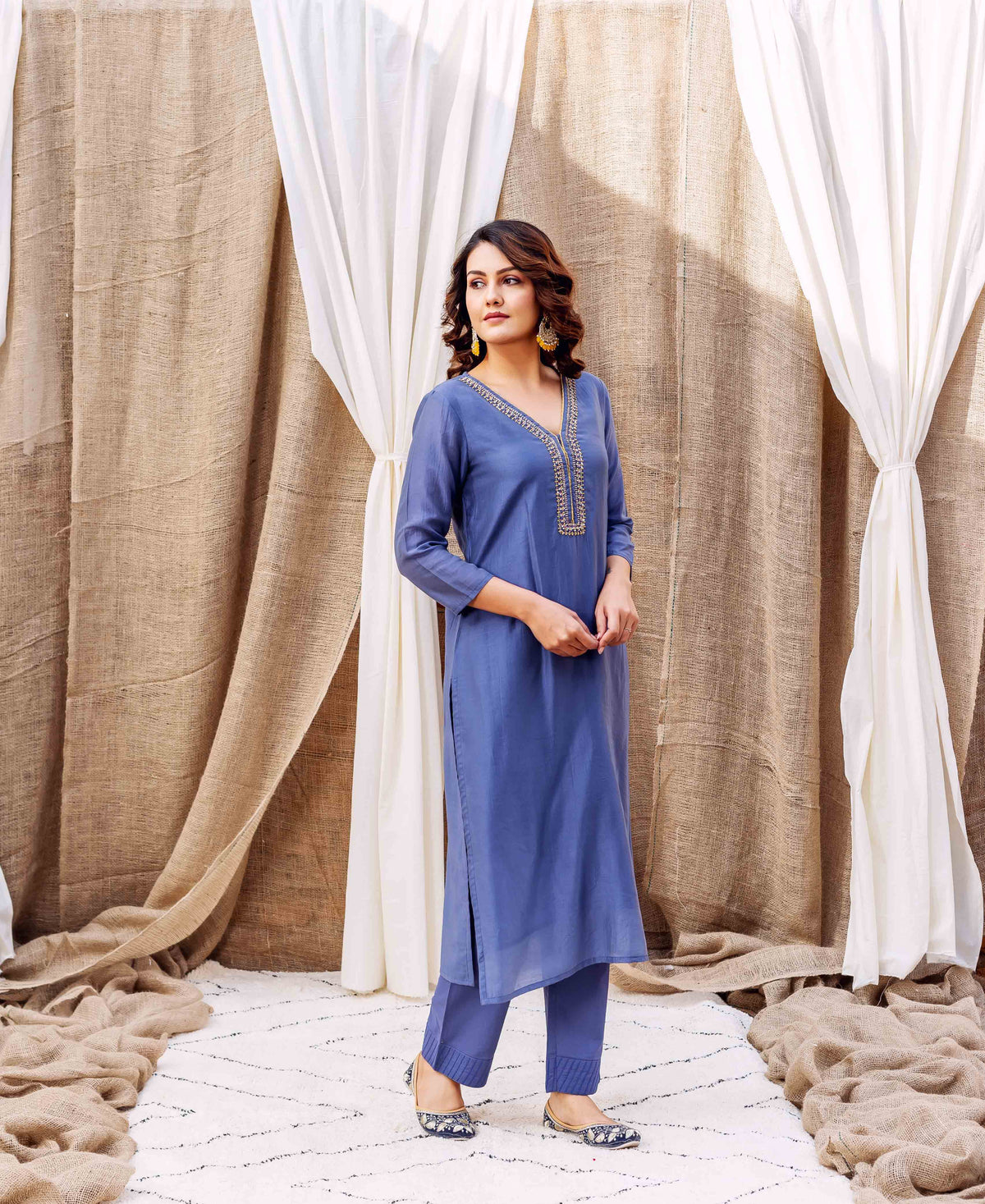 Full-length model in steel blue kurta and pants with golden embroidered V-neckline.