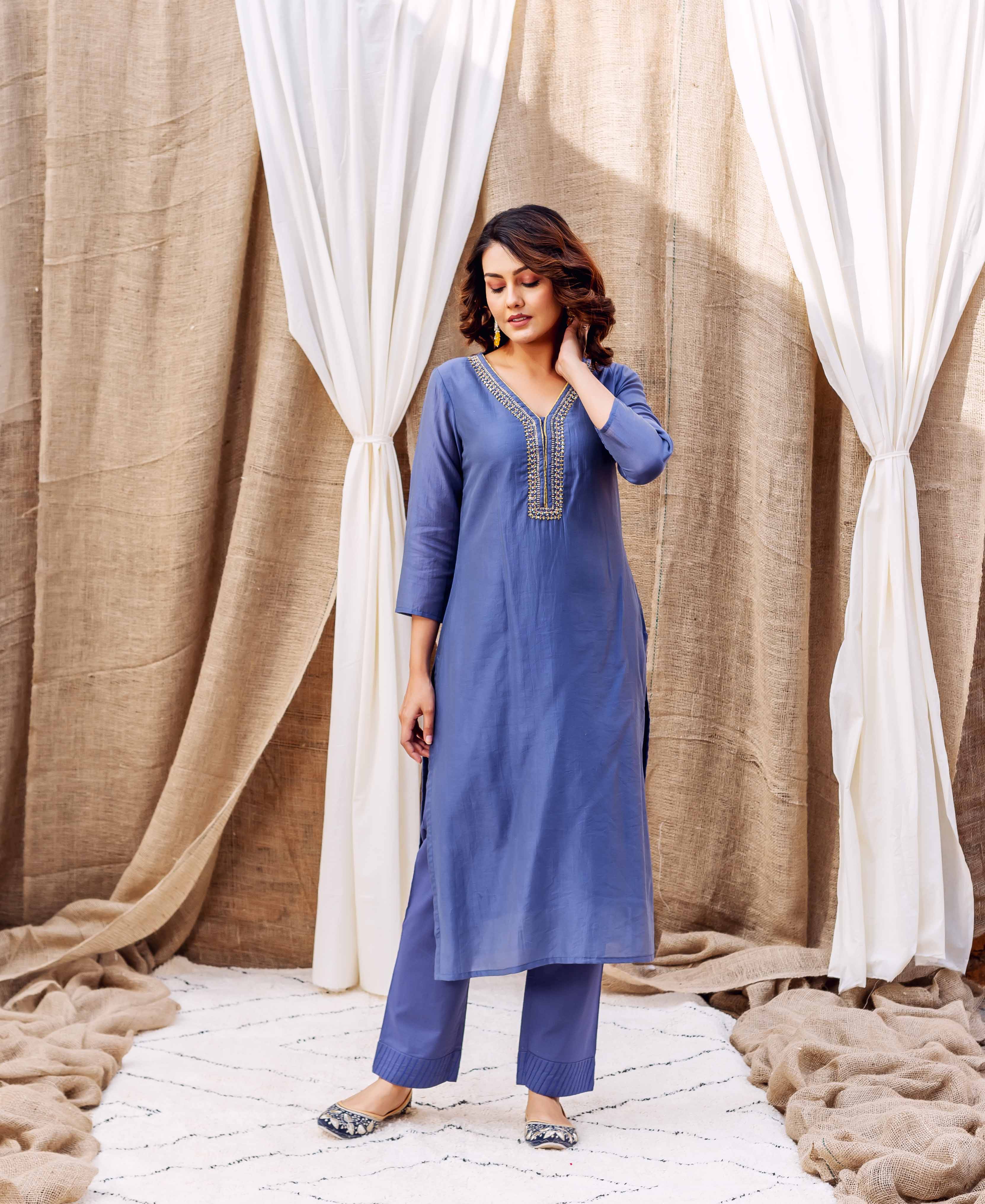 Woman models steel blue kurta with matching pants, featuring golden embroidered V-neck.