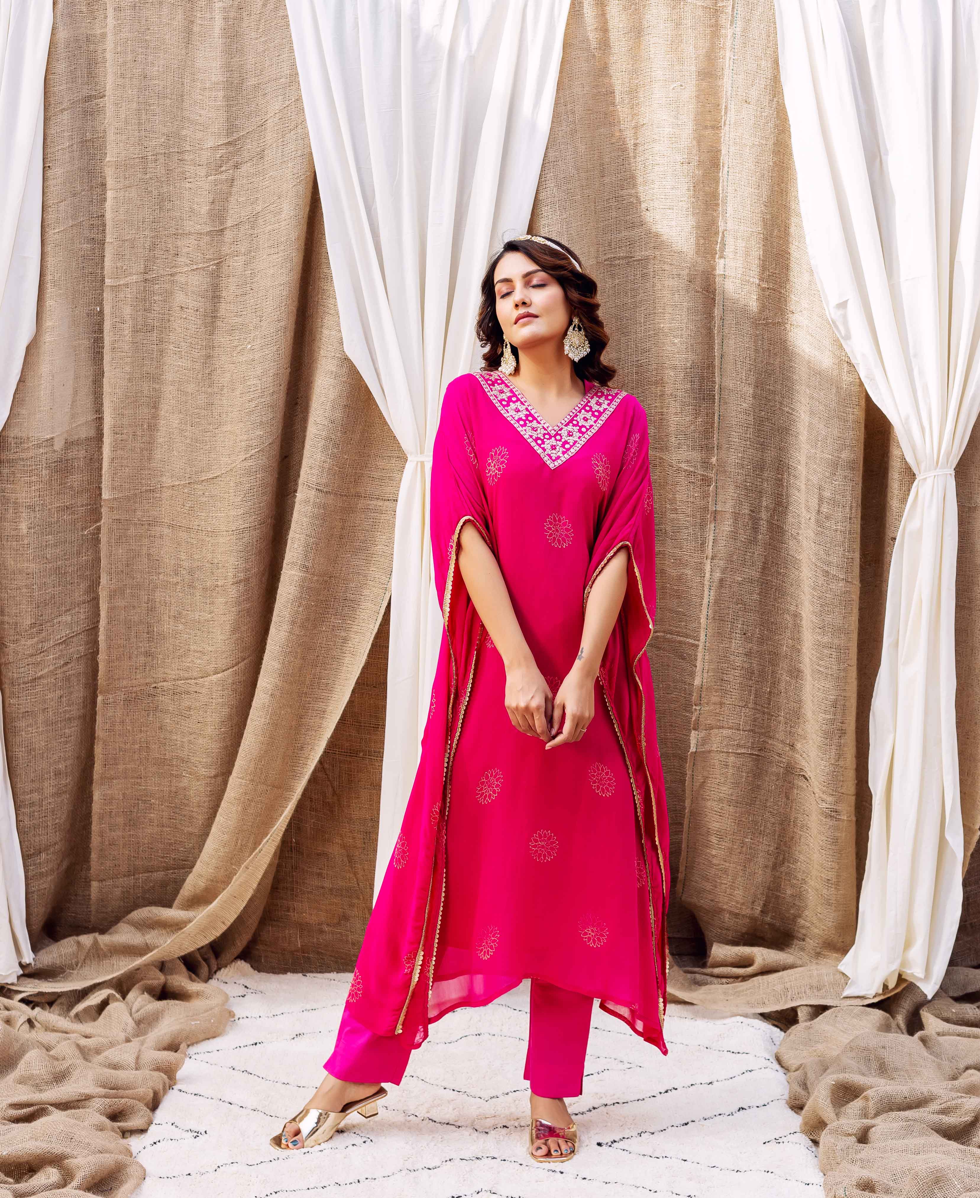 Model in full-length magenta kaftan with gold embroidered V-neck and block print motifs.
