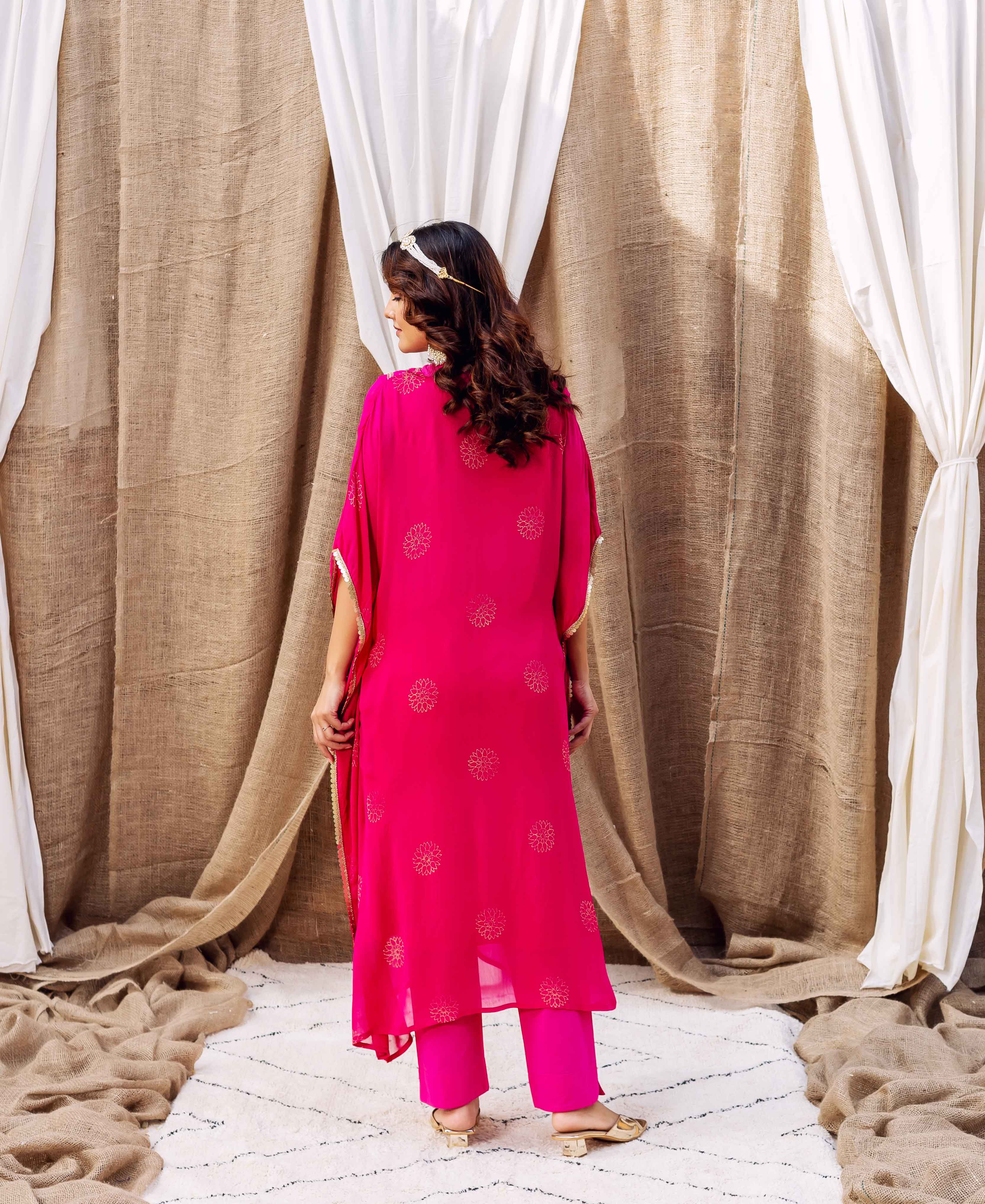 Rear view: model in a magenta ethnic kaftan with gold floral motifs and matching pants.