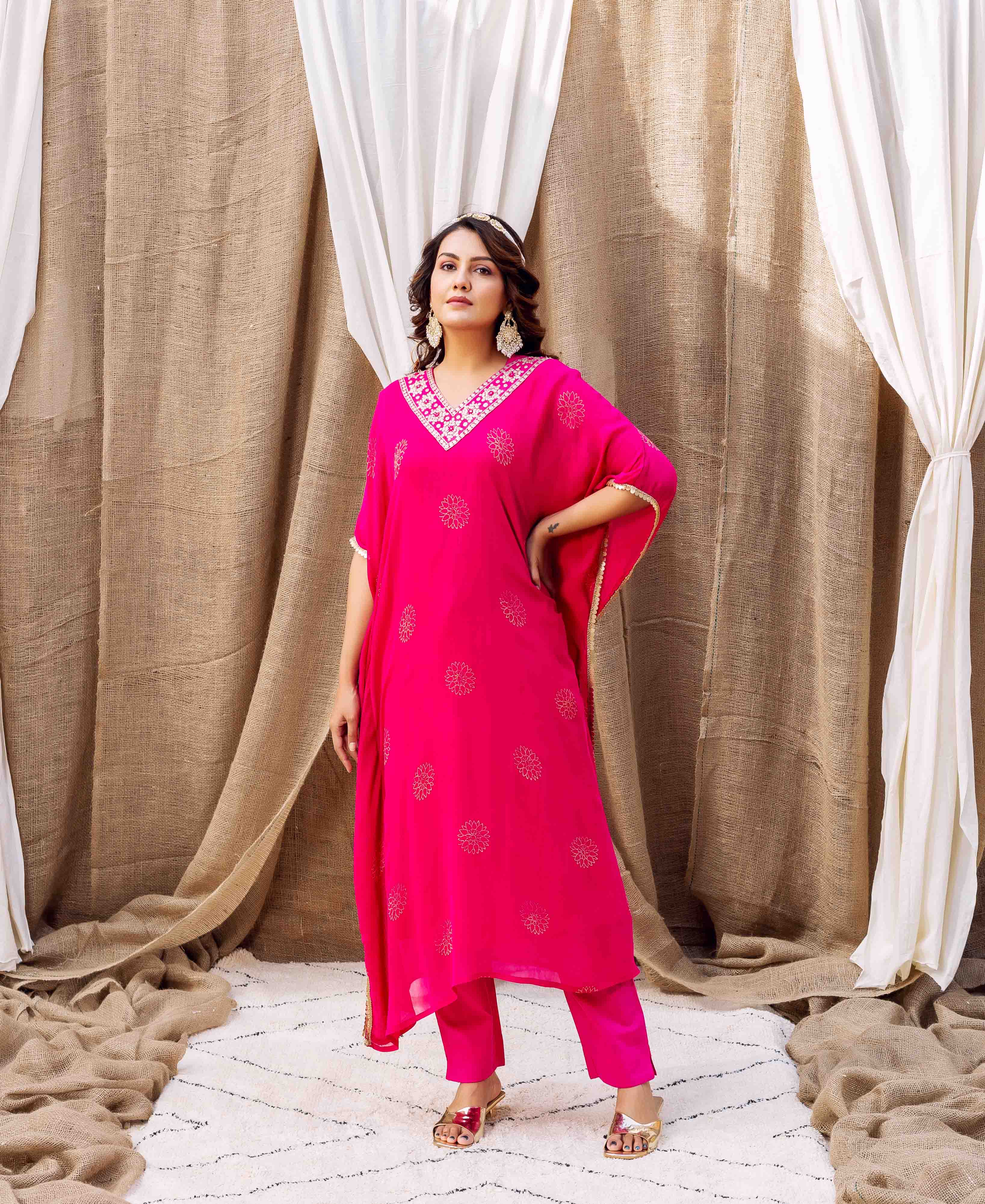 Full-body shot of model wearing magenta kaftan with embroidered V-neckline and golden floral block prints.