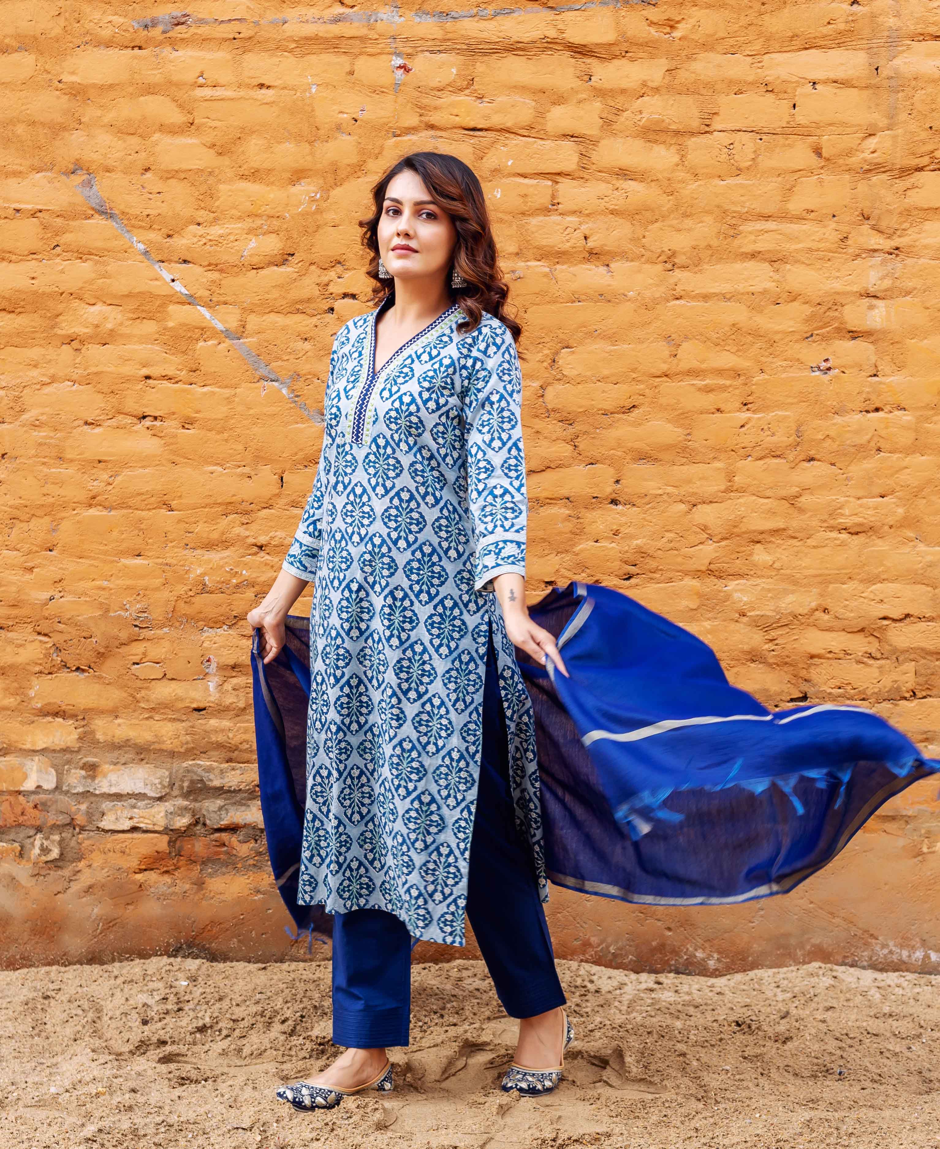Standing model wears blue and white block-printed kurta set with a flowing indigo dupatta.