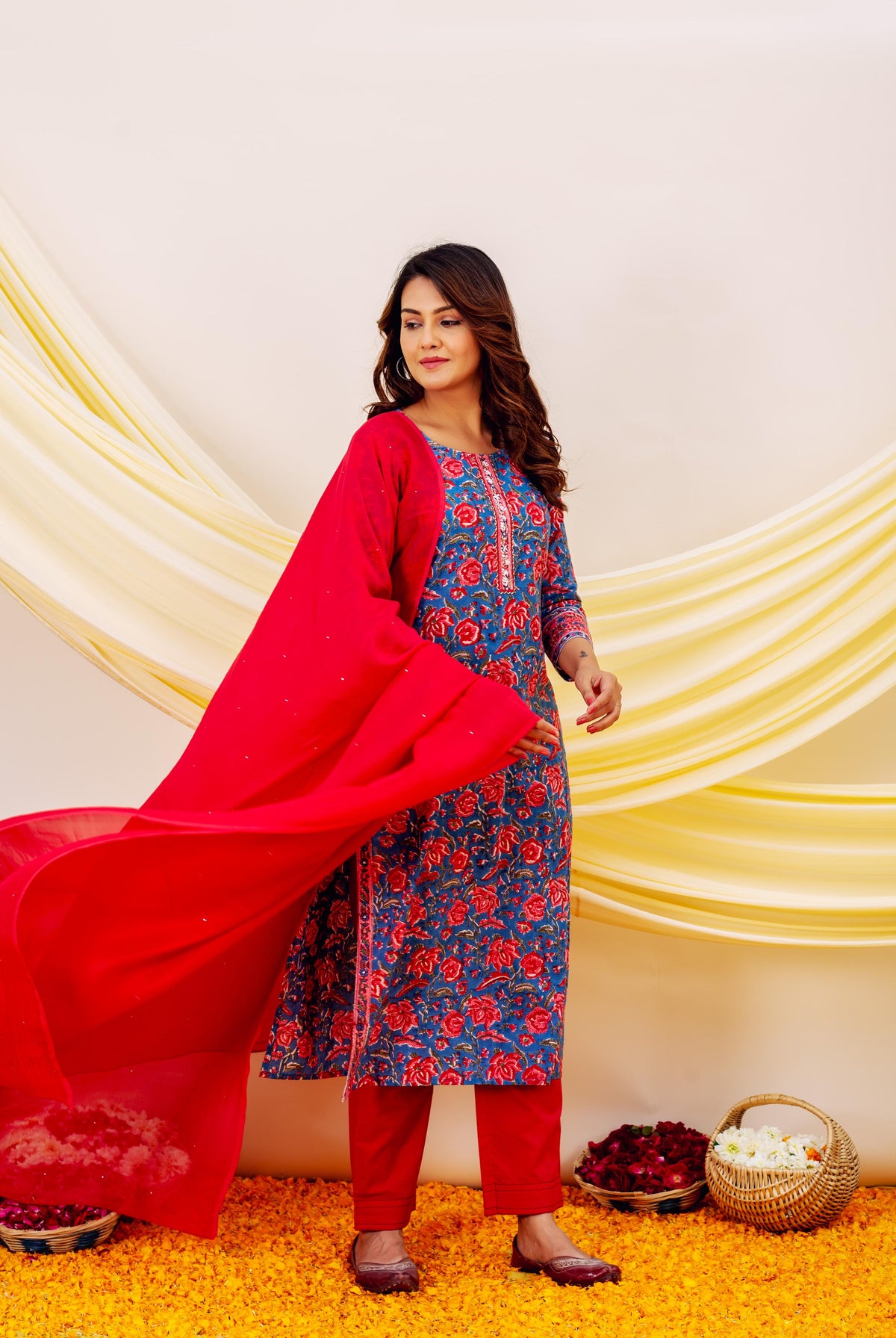 Model wears blue floral hand-block-printed kurta with red embroidered dupatta and straight pants.
