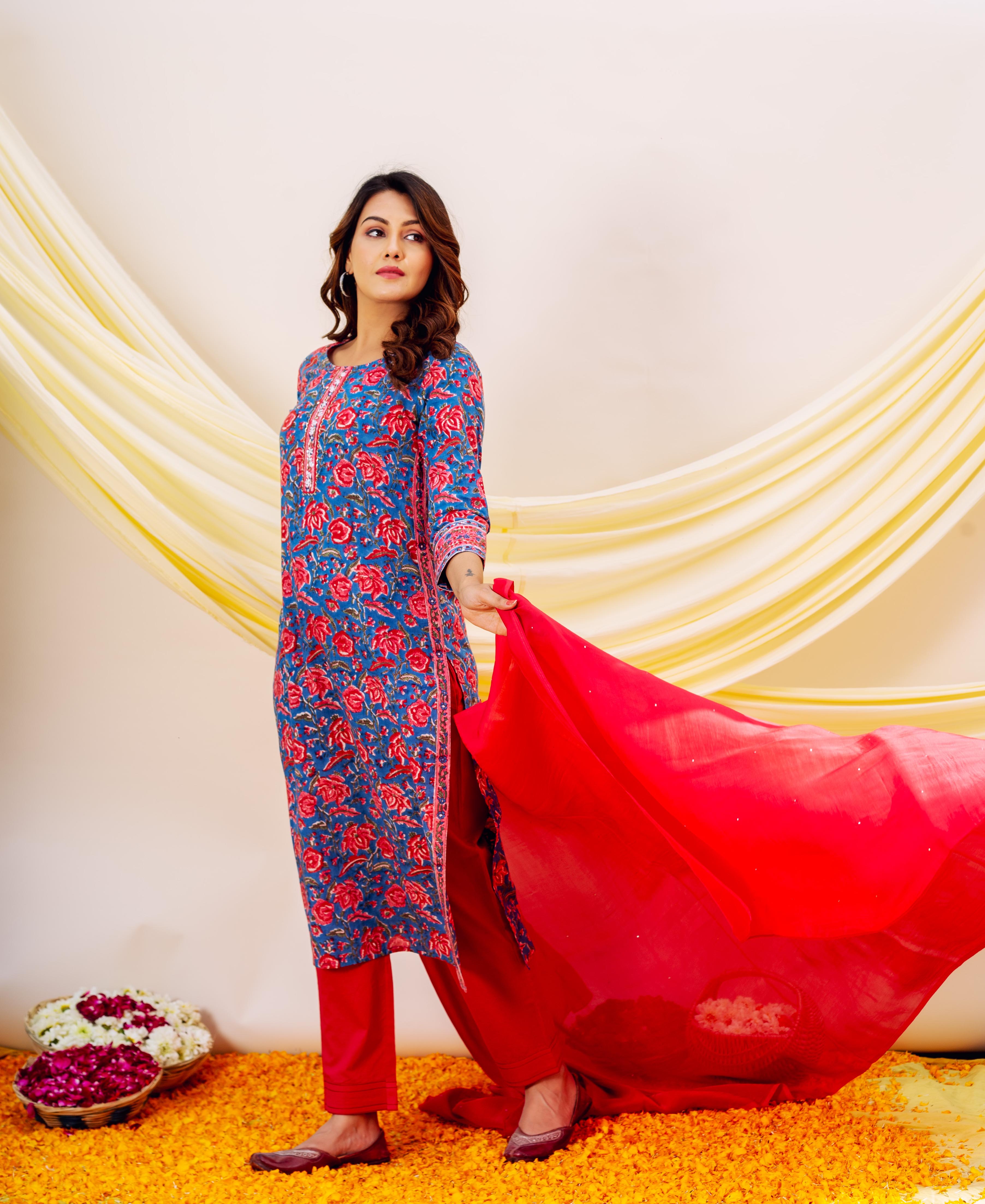 Full shot of woman in blue floral print kurta, red bottoms, and flowy red dupatta.