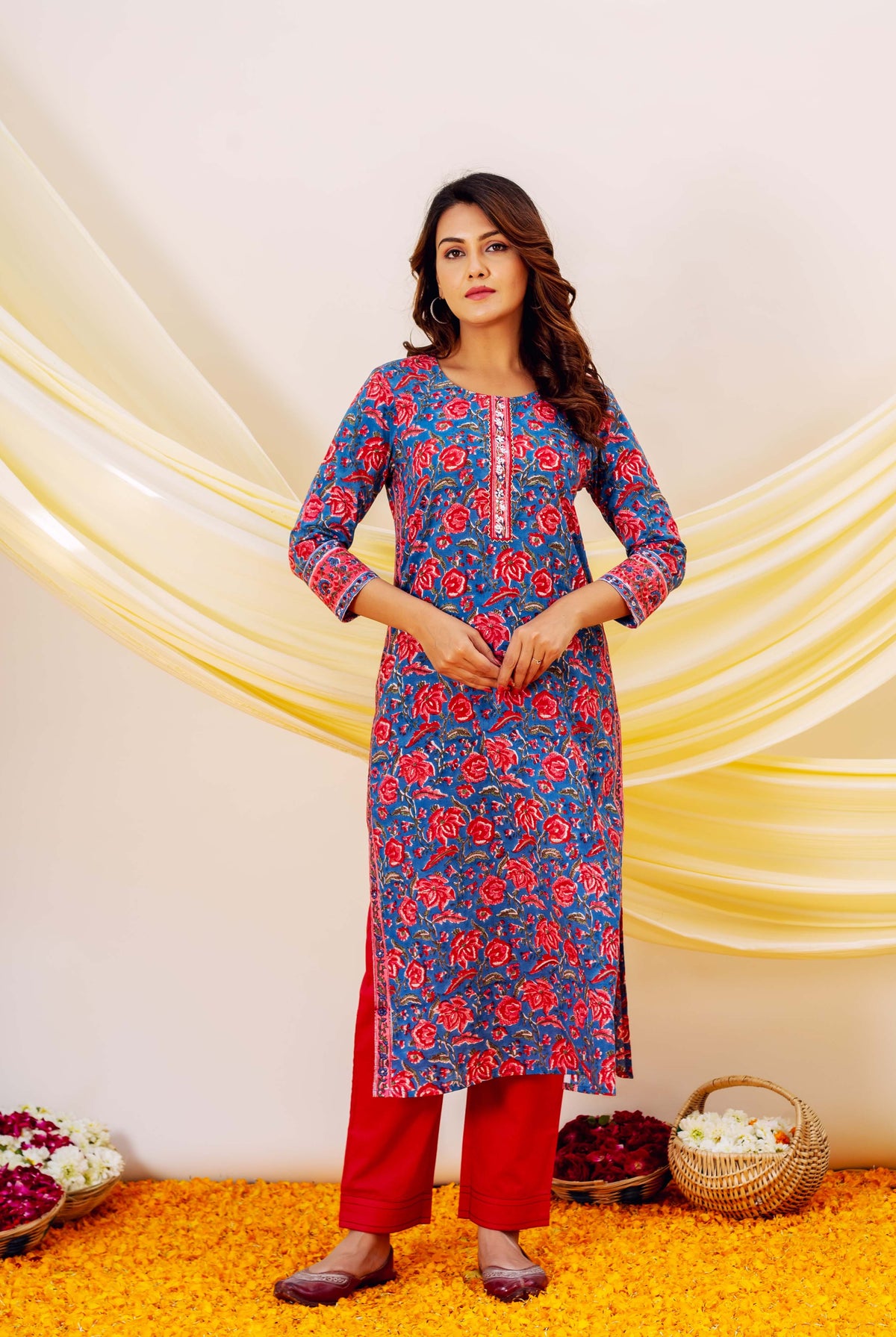 Front view full look of model wearing blue embroidered hand-block-printed floral kurta with red bottoms.