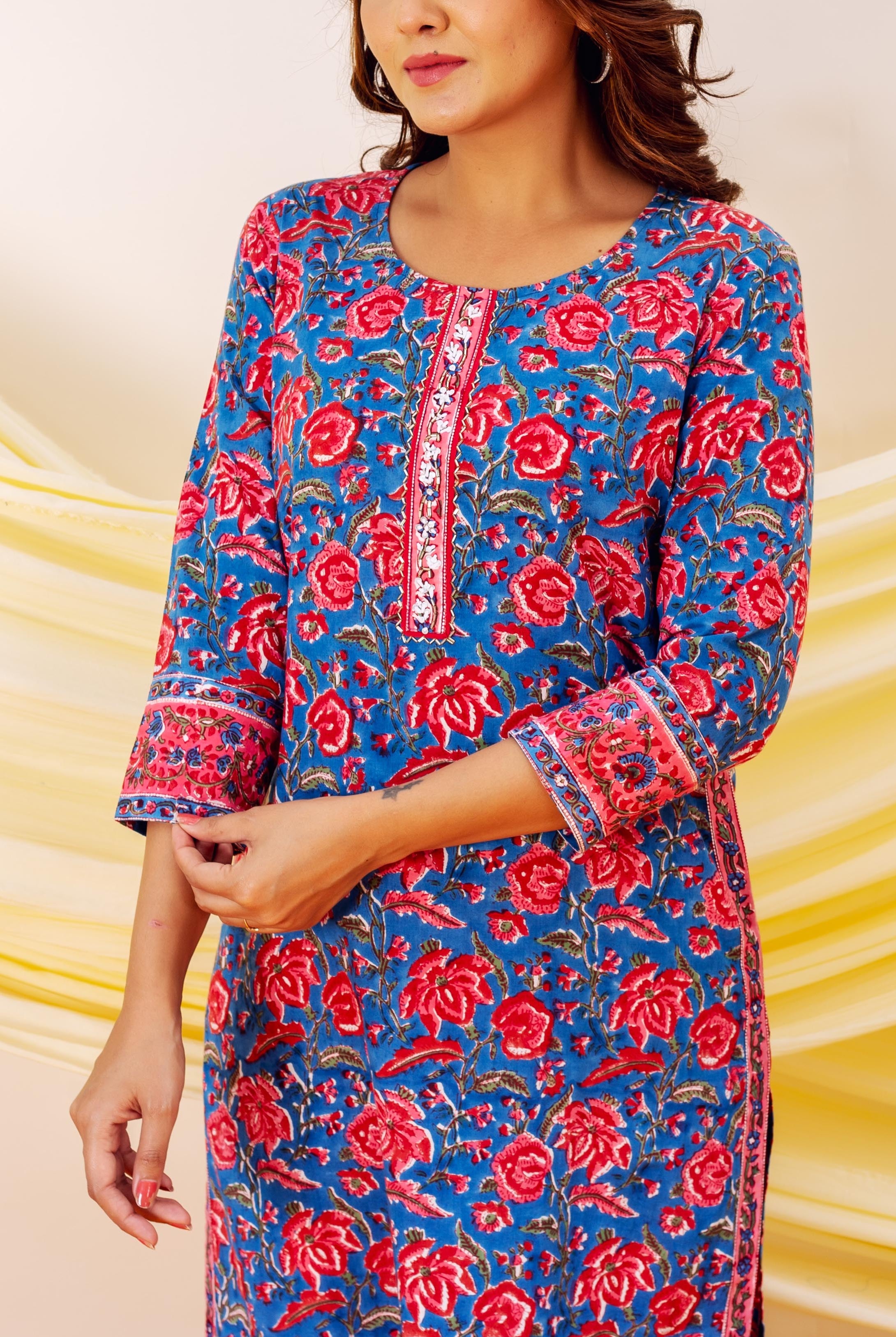Model wearing a blue hand-block print kurta with vibrant red floral patterns and embroidered placket.