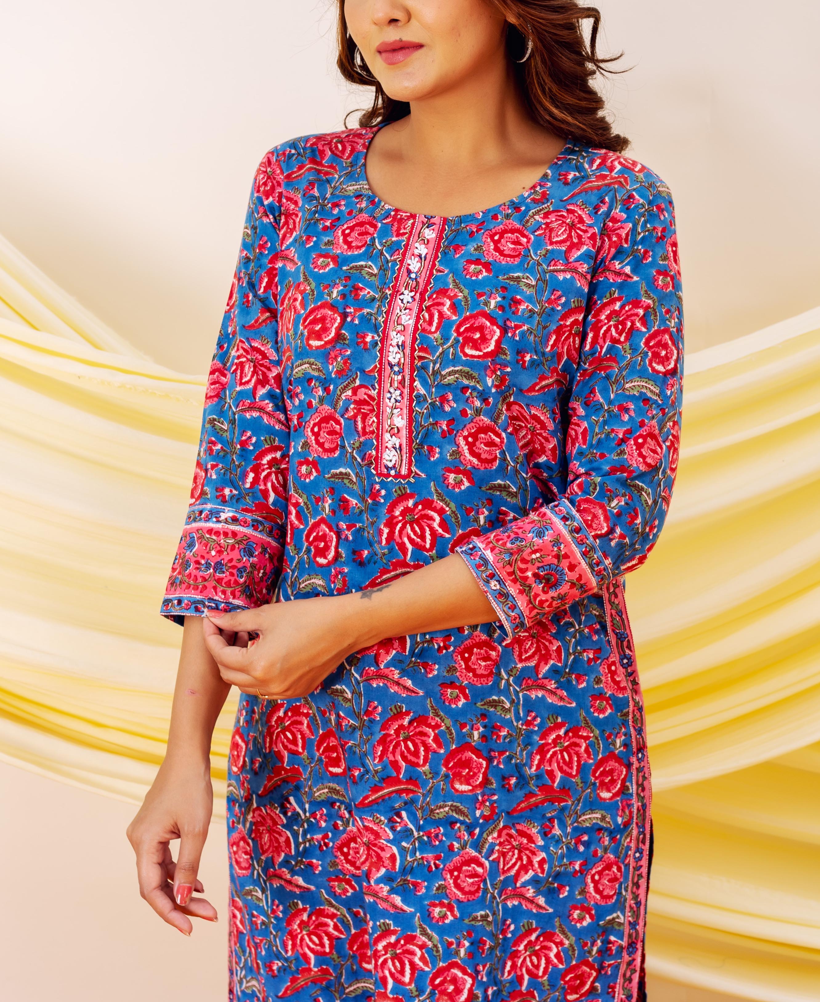 Model wearing a blue hand-block print kurta with vibrant red floral patterns and embroidered placket.