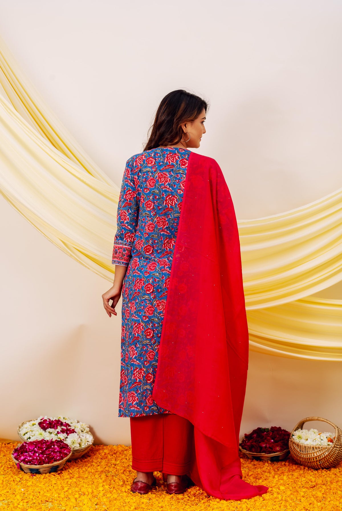 Back view: Model in blue floral hand-block printed kurta, red pants, and matching dupatta.