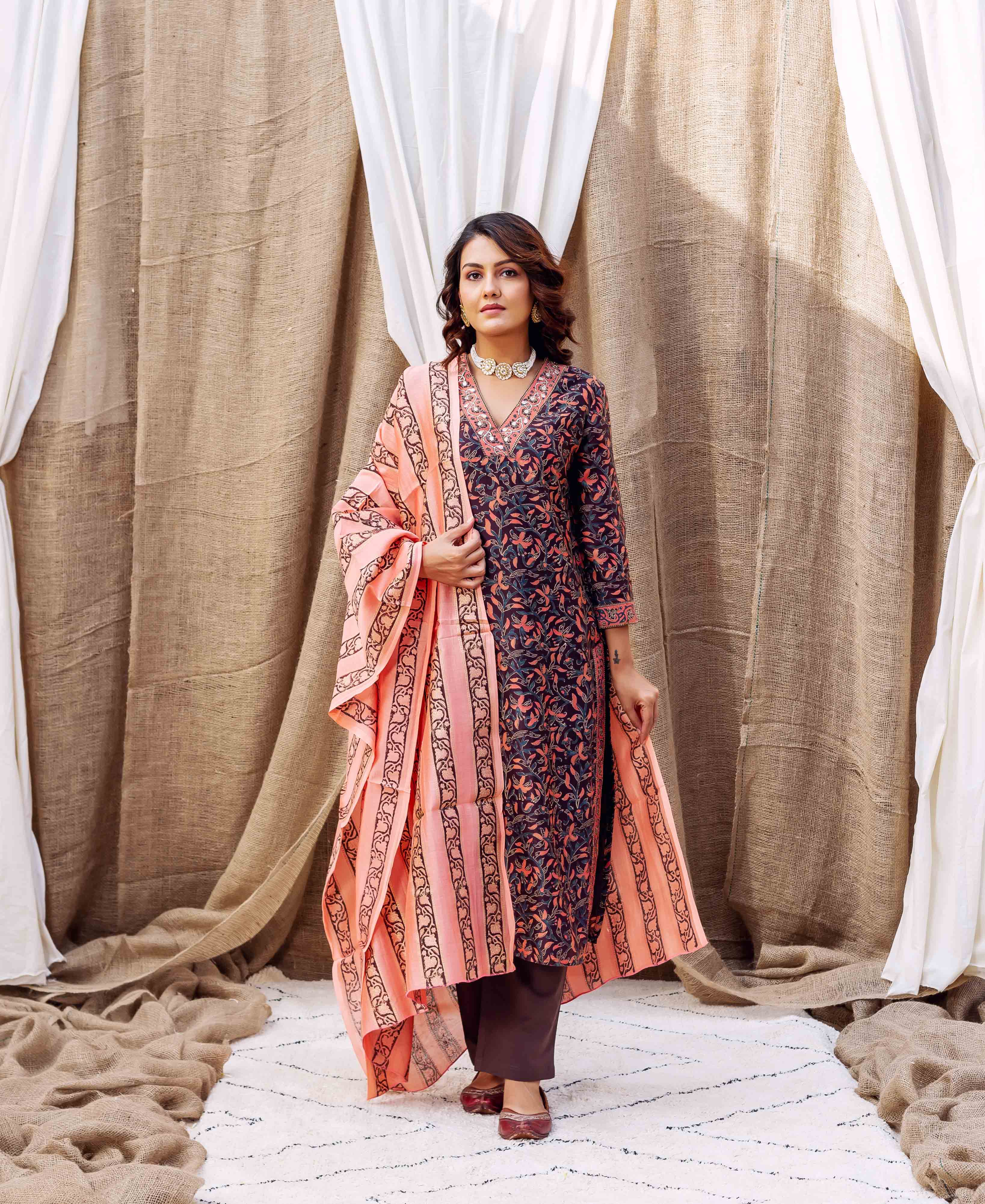 Woman wearing dark blue and peach hand-block-printed silk kurta with floral patterns and accessories.