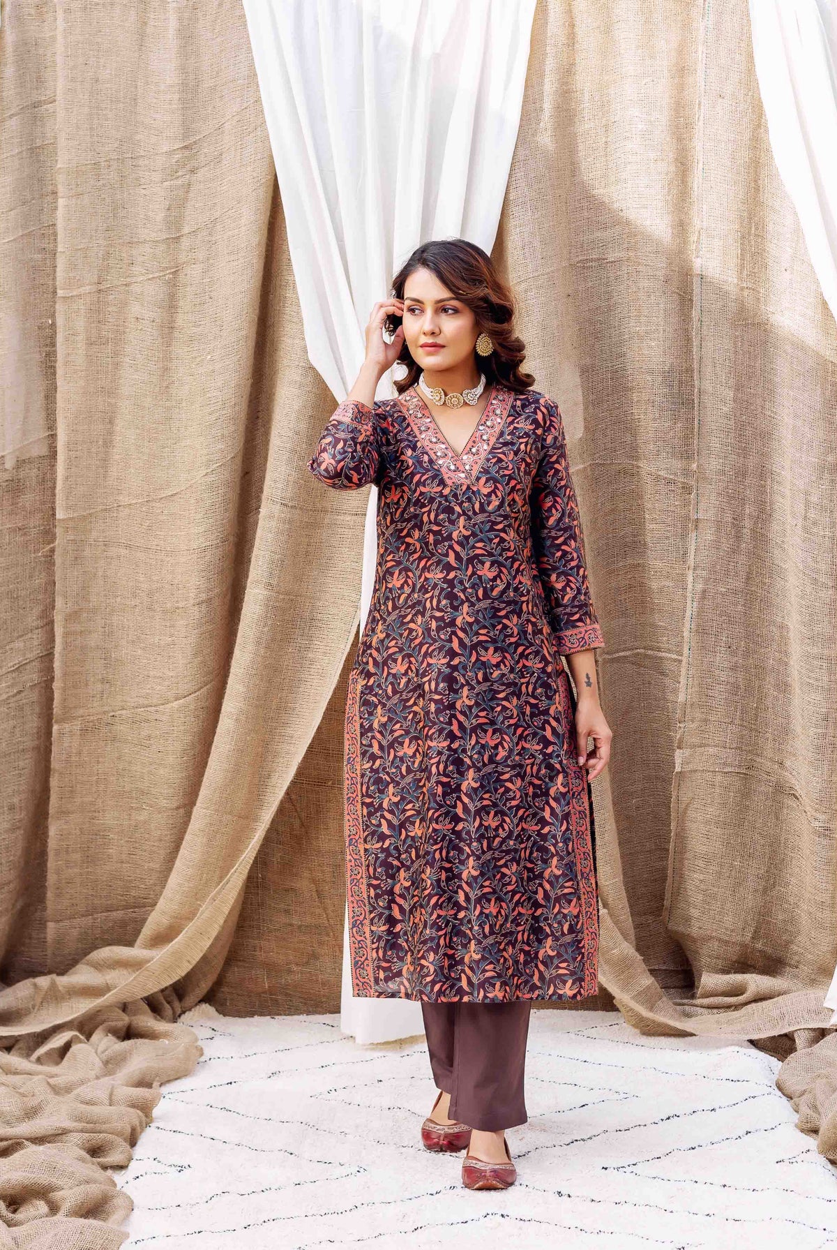 Woman wearing dark purple silk kurta with orange and blue floral hand-block print and gold accents.