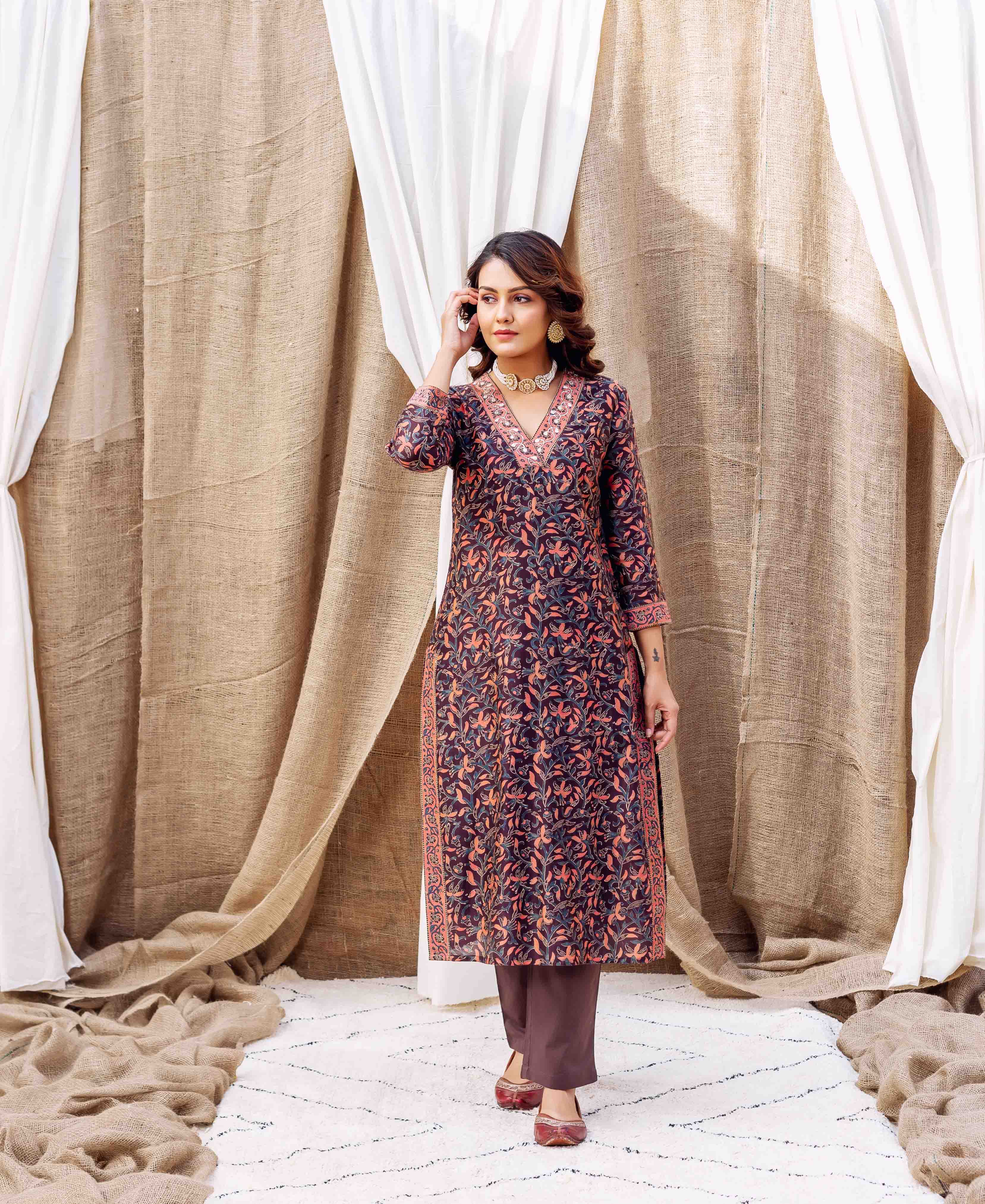 Woman wearing dark purple silk kurta with orange and blue floral hand-block print and gold accents.