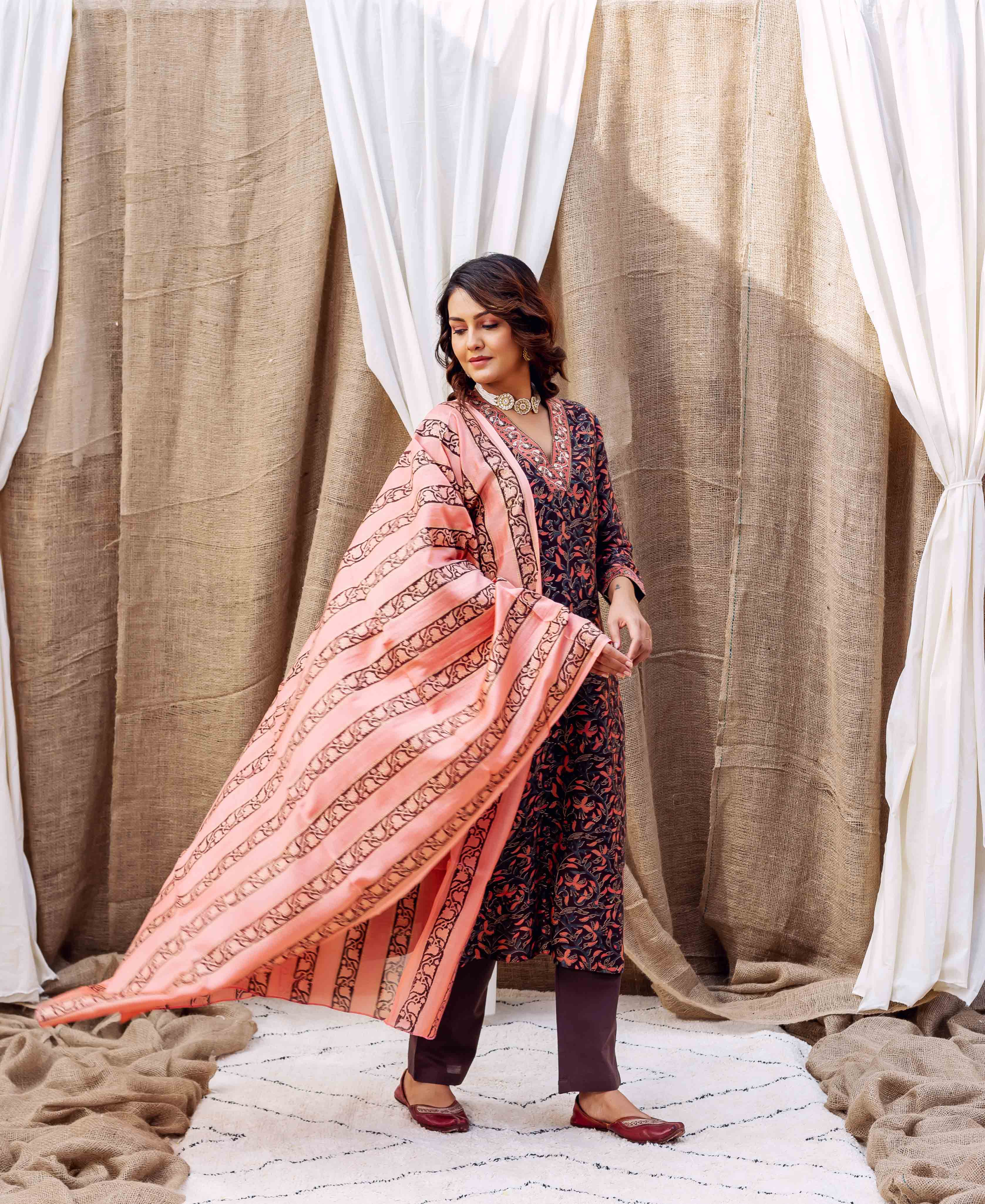Angled shot of model wearing a flowing peach hand-block printed dupatta with black stripes.