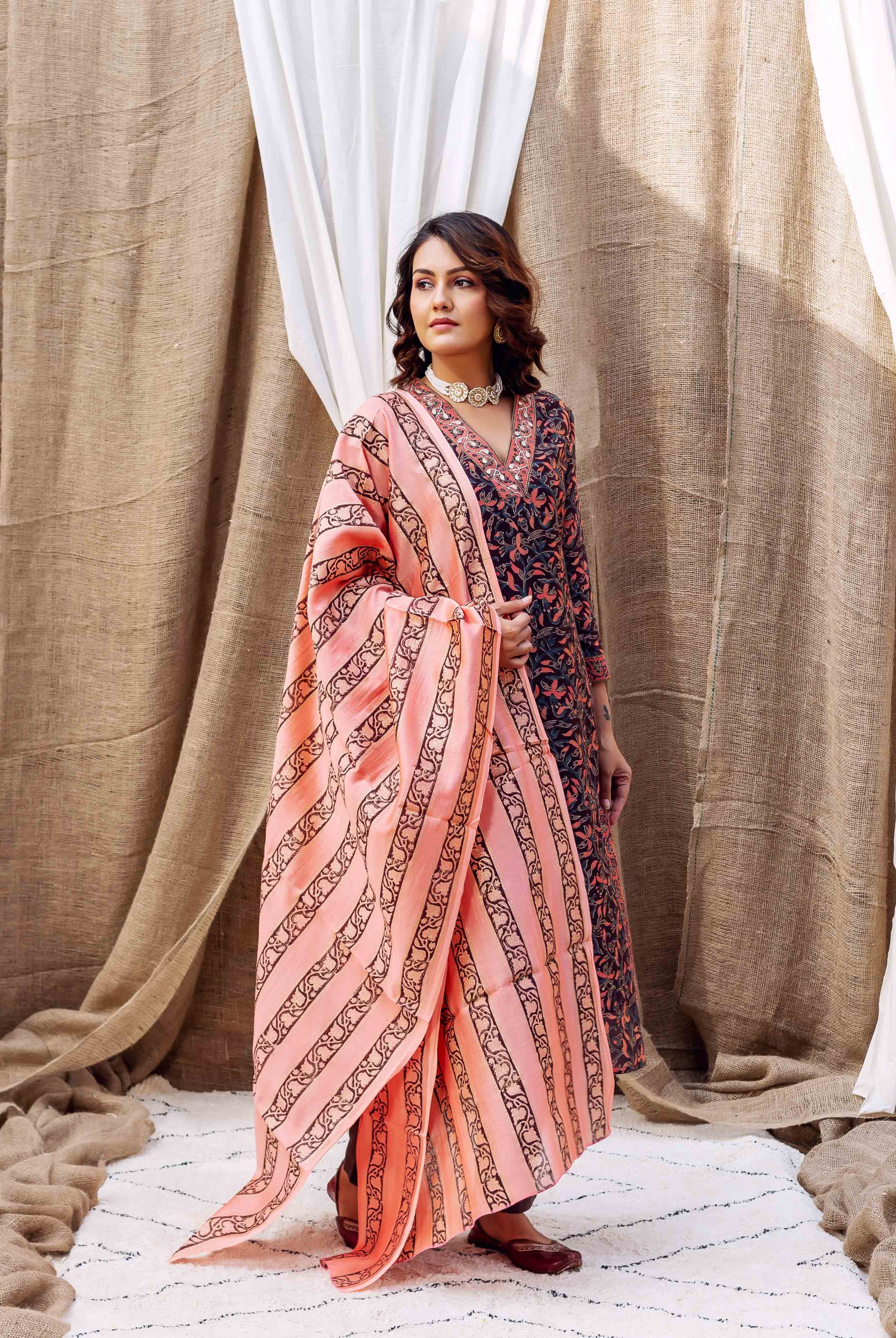 Model in a navy blue floral kurta with a vibrant peach and black striped dupatta, front view.