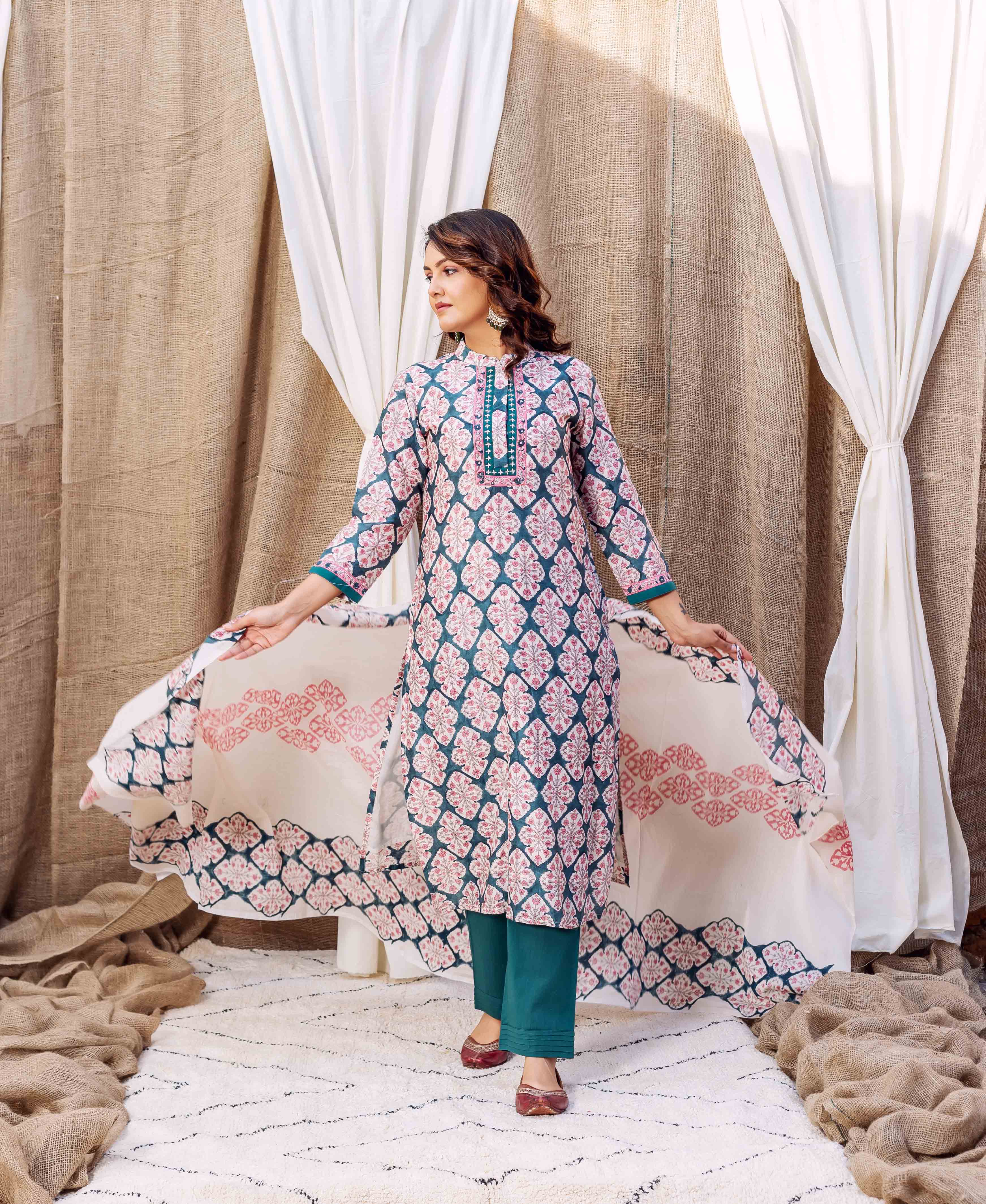A woman models a teal green block-printed kurta with pink floral patterns.
