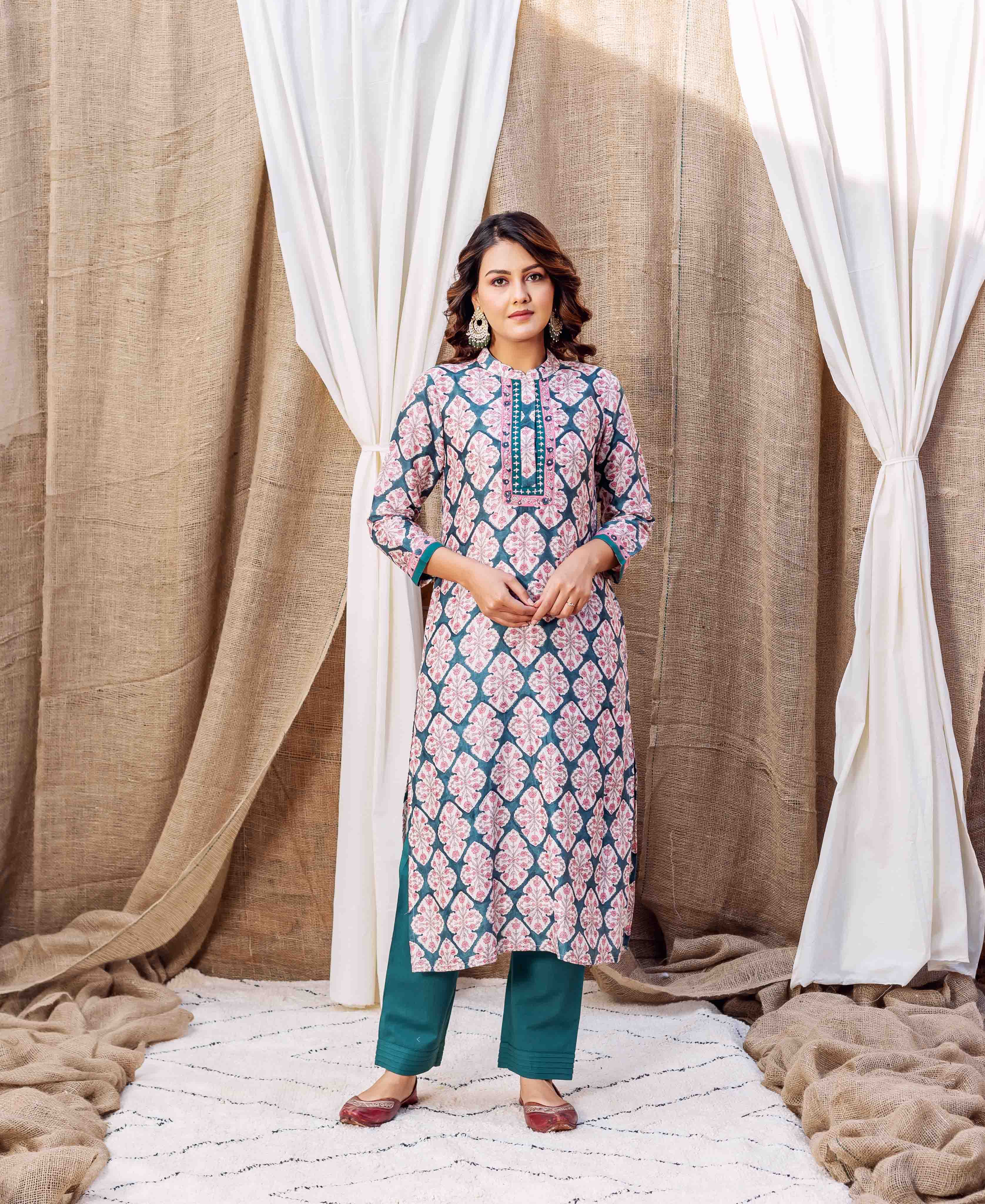 A model wearing a teal green block-printed kurta with pink floral patterns.
