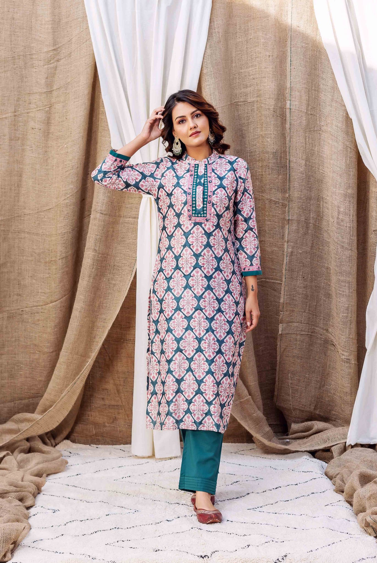 Model wearing a teal green block printed kurta with pink patterns and matching solid pants.