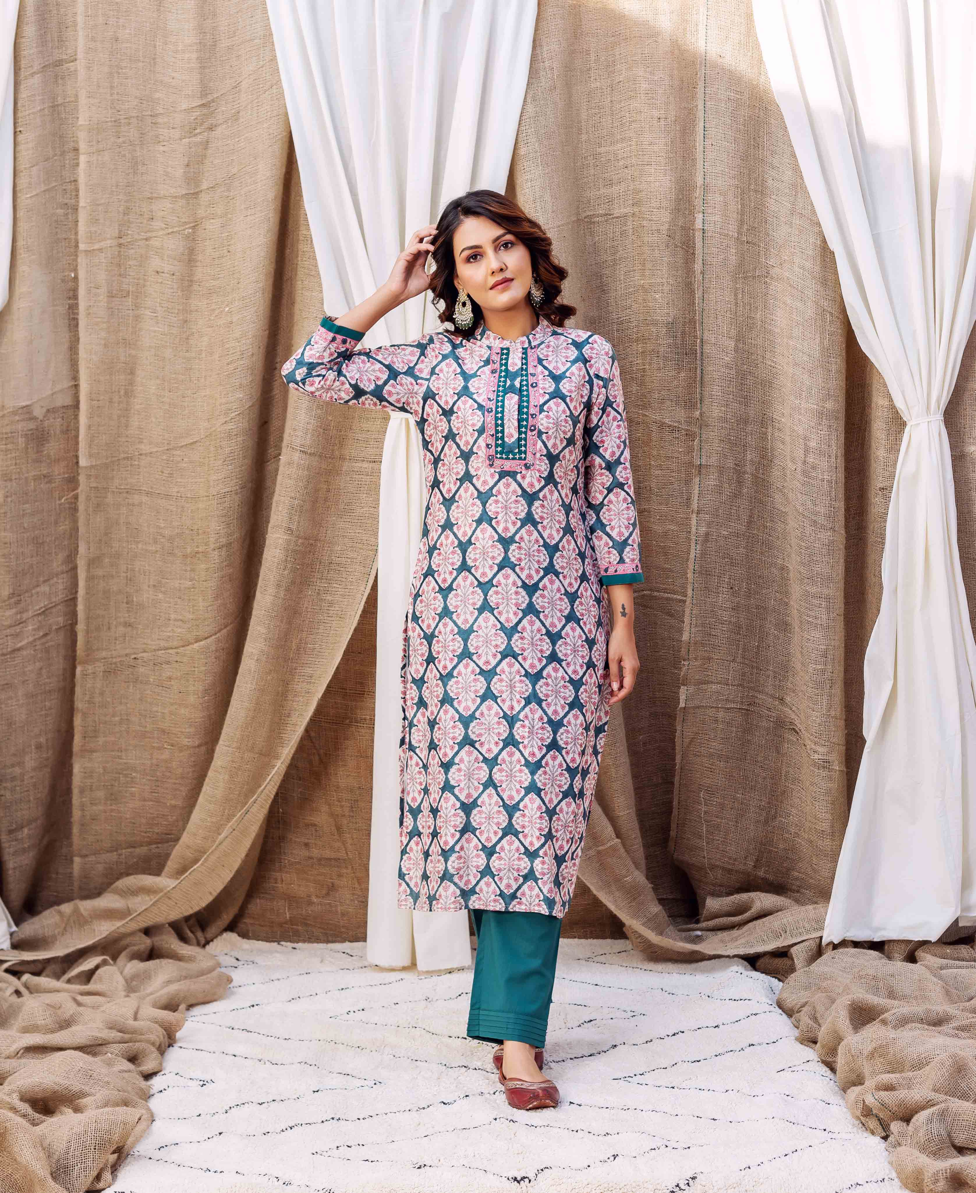 Model wearing a teal green block printed kurta with pink patterns and matching solid pants.