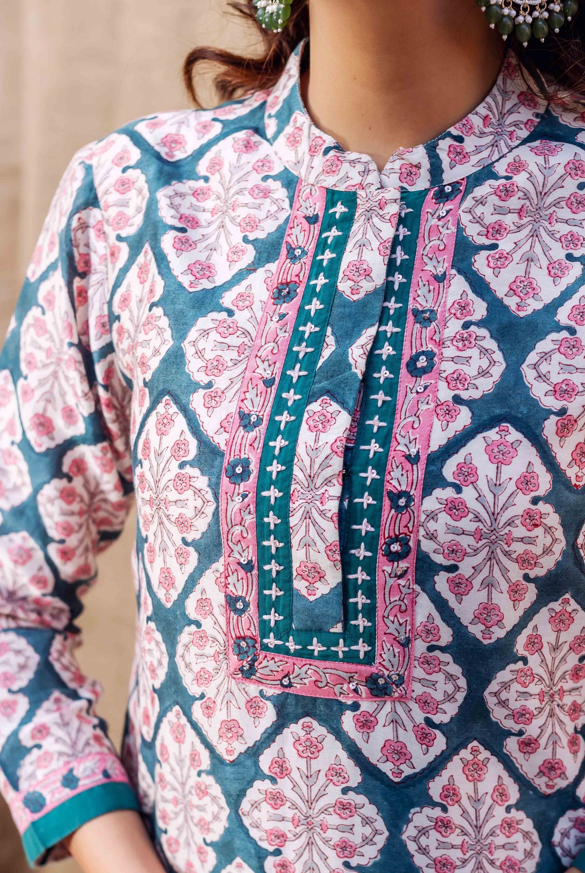 Close-up of model in teal green and pink hand-block-printed kurta with geometric floral patterns.