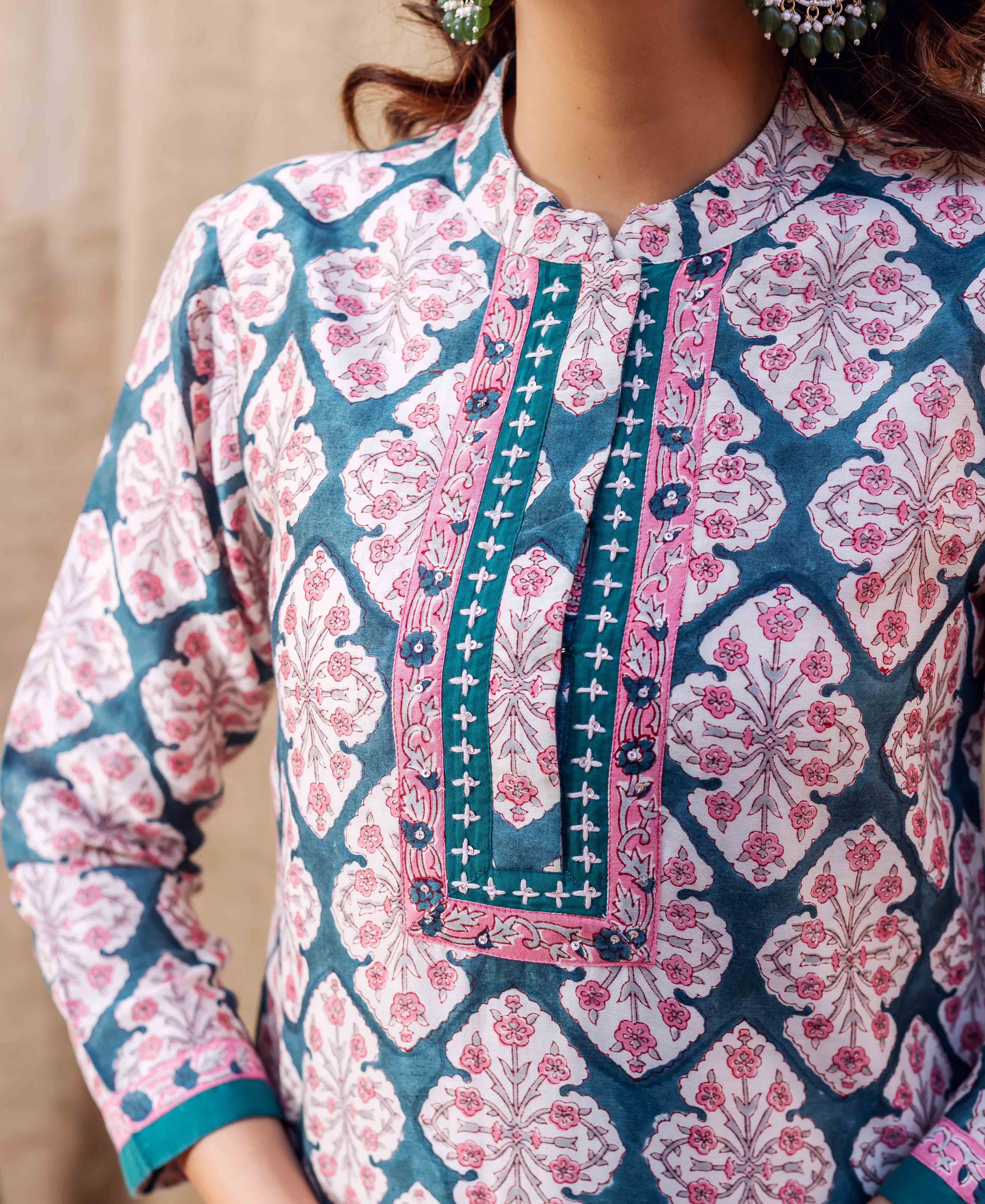 Close-up of model in teal green and pink hand-block-printed kurta with geometric floral patterns.
