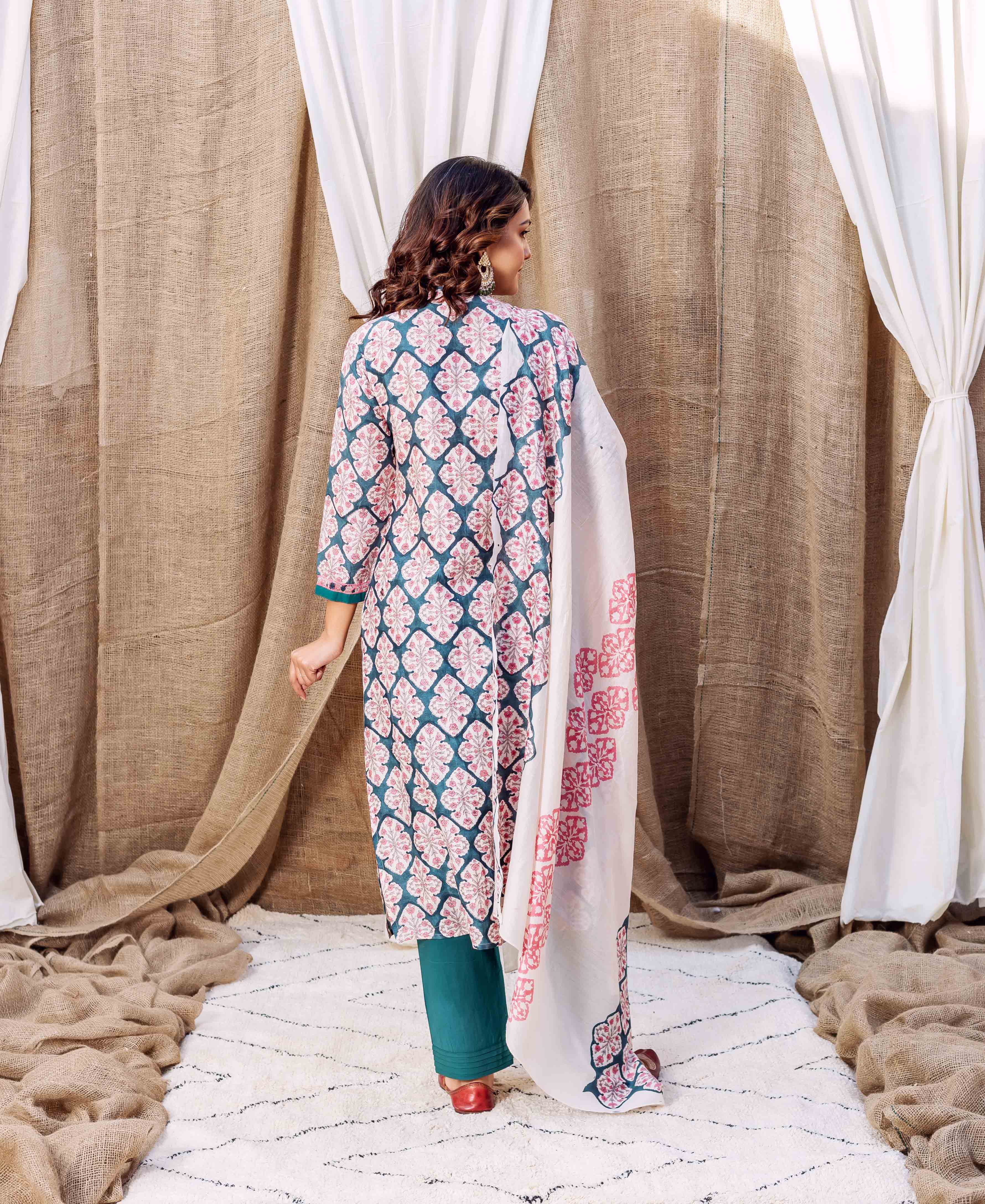 Back view of model in teal green block printed kurta, pink motifs, and white dupatta.