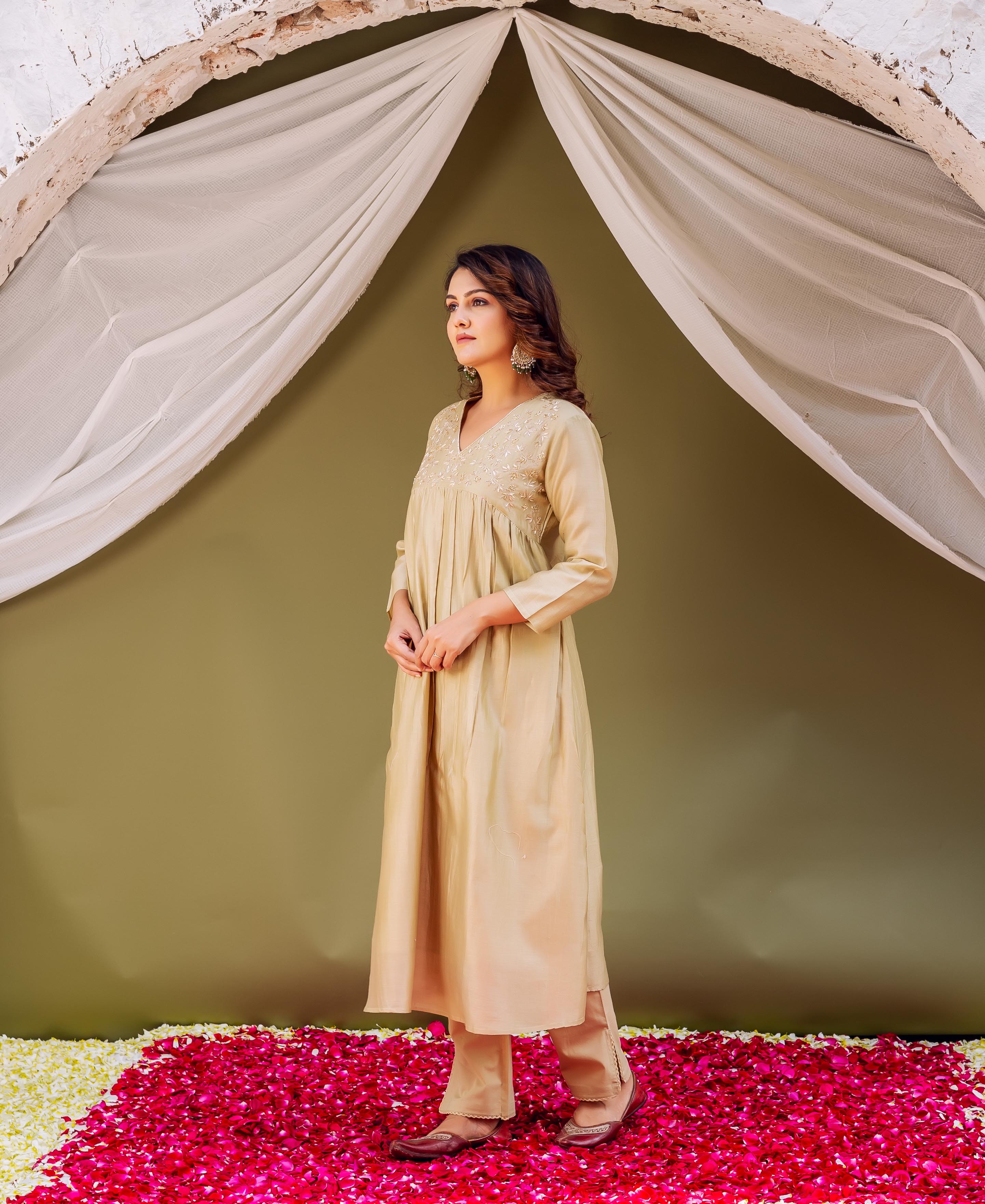 Full-body view of a woman wearing a light golden-beige kurta set with embroidered V-neck yoke.