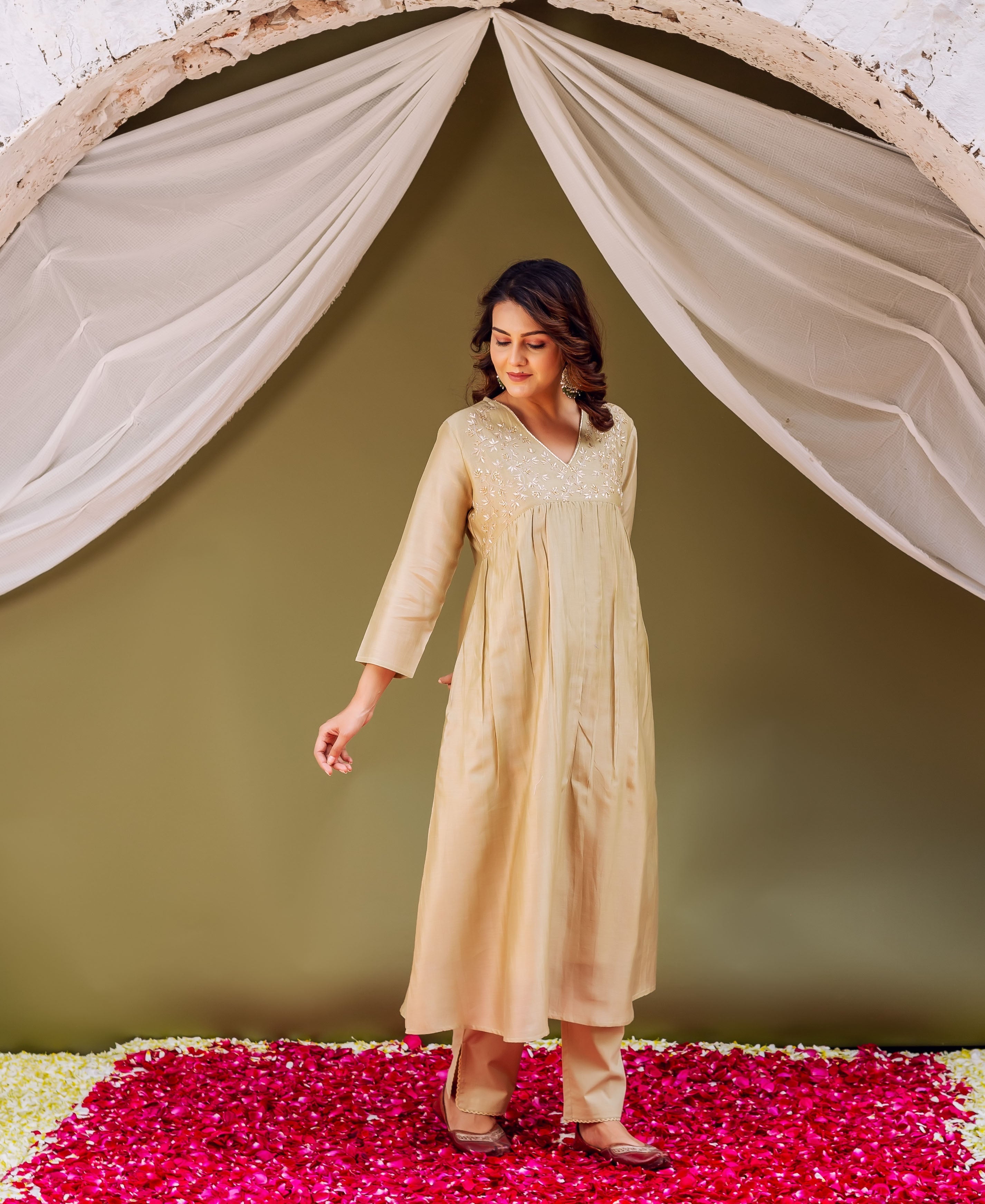 Female model in a full-length light golden pleated kurti, embroidered V-neck, and matching trousers.