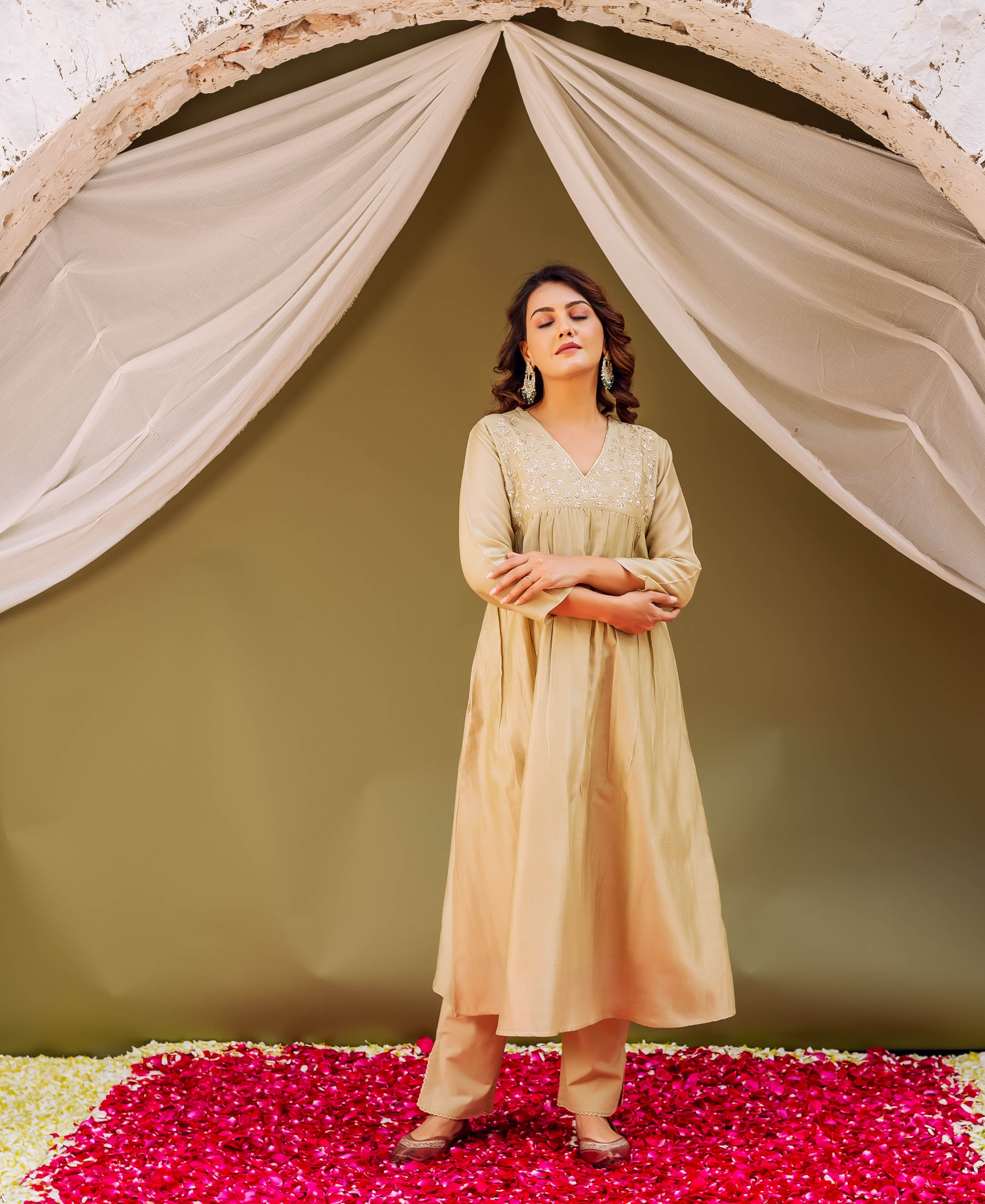 On a model, full-length, wearing a light golden-beige ethnic kurta set with embroidered V-neck.