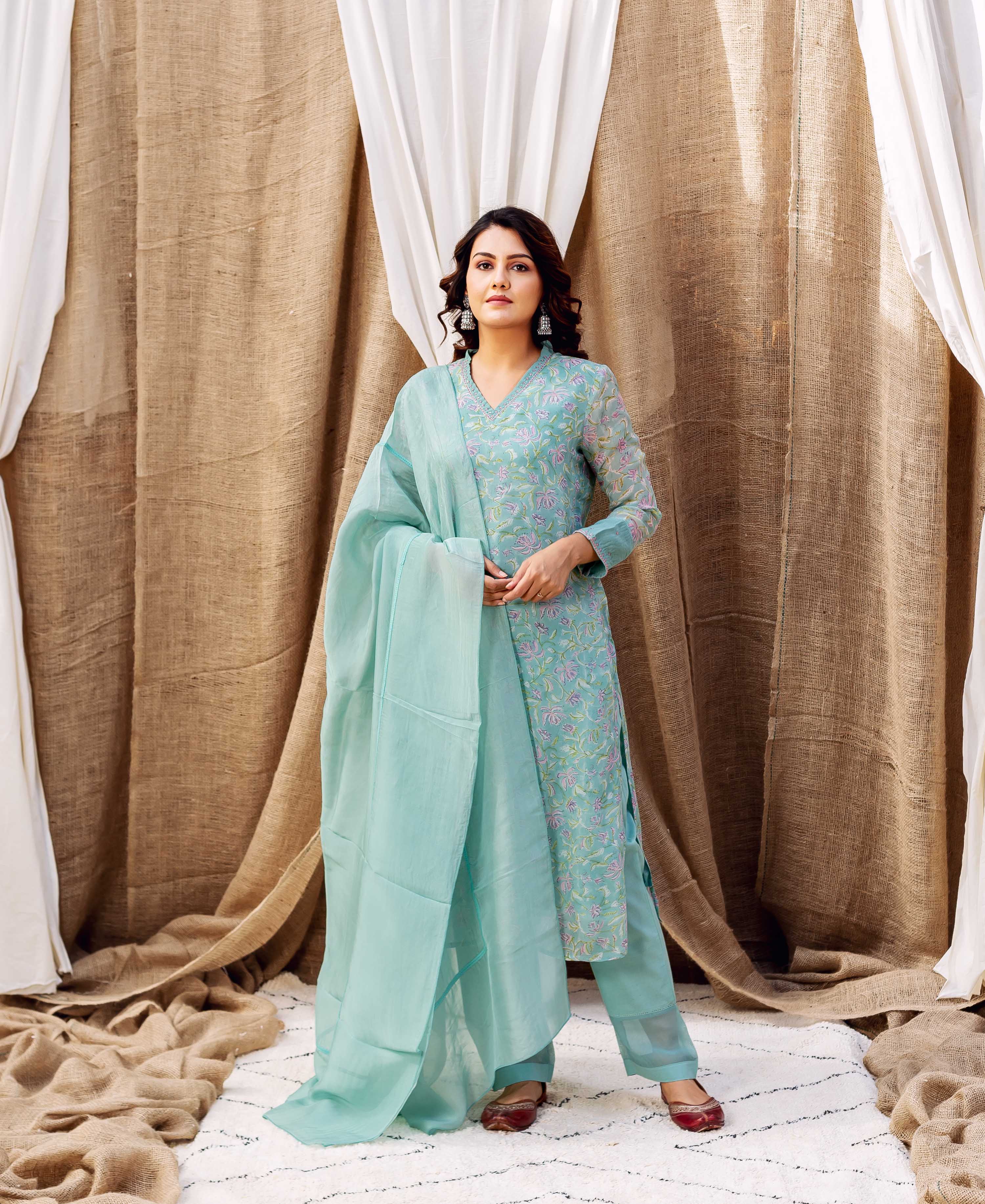 A woman in a turquoise kurta with a floral print and matching dupatta.