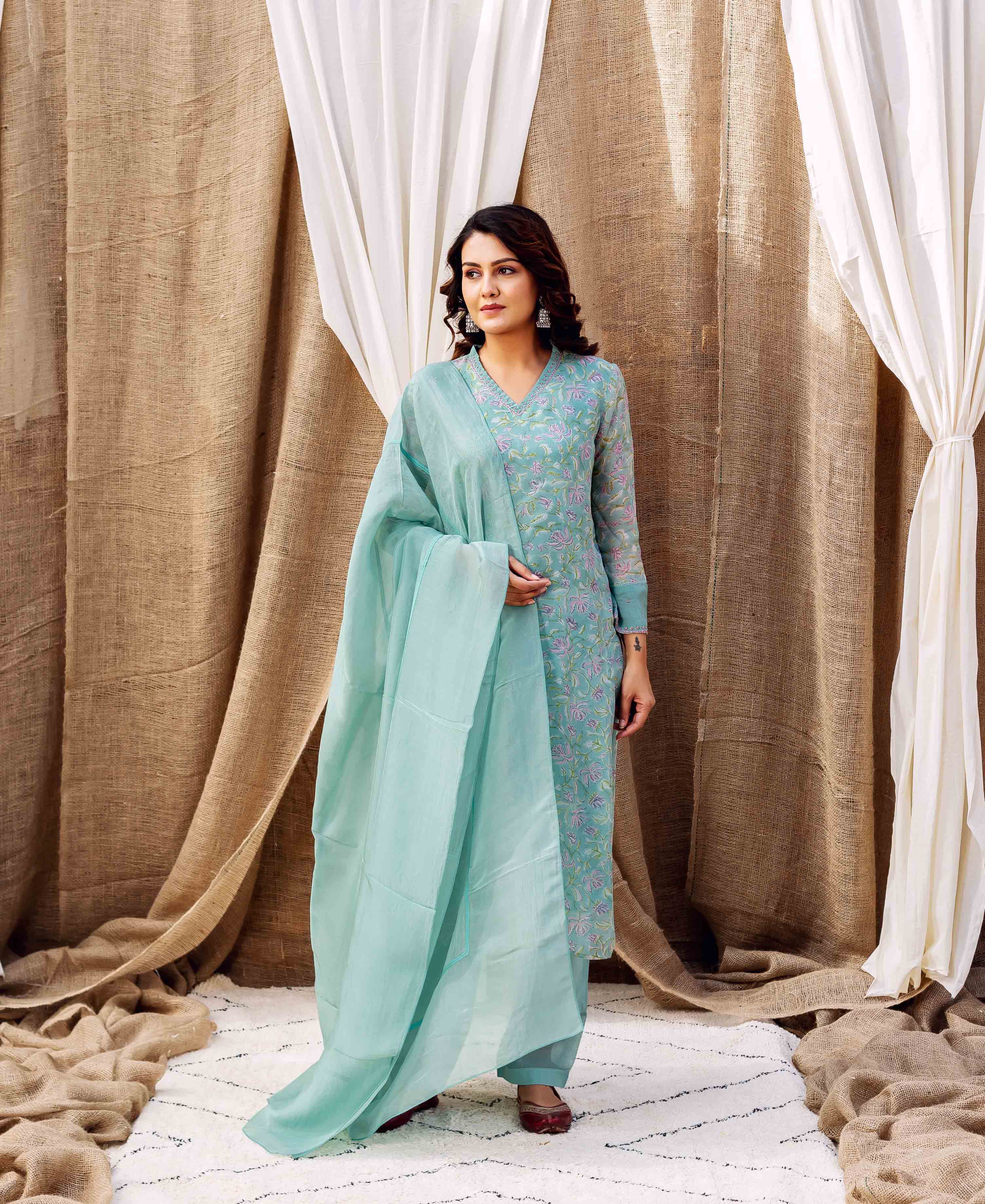 Woman wearing a turquoise hand-block-printed floral kurta set with a sheer dupatta.