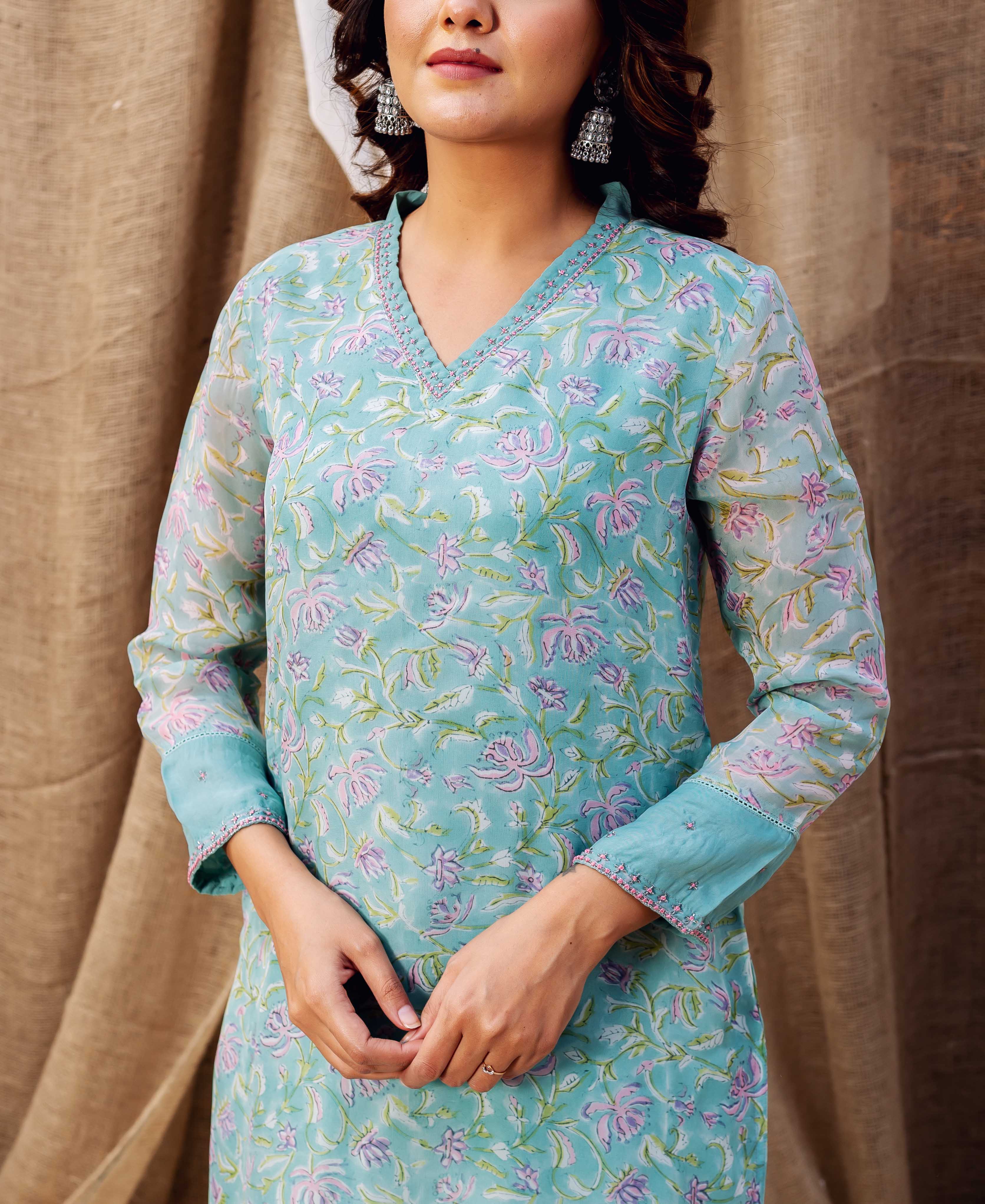 Model wears a turquoise organza kurta with pink and purple hand-block-printed floral patterns.