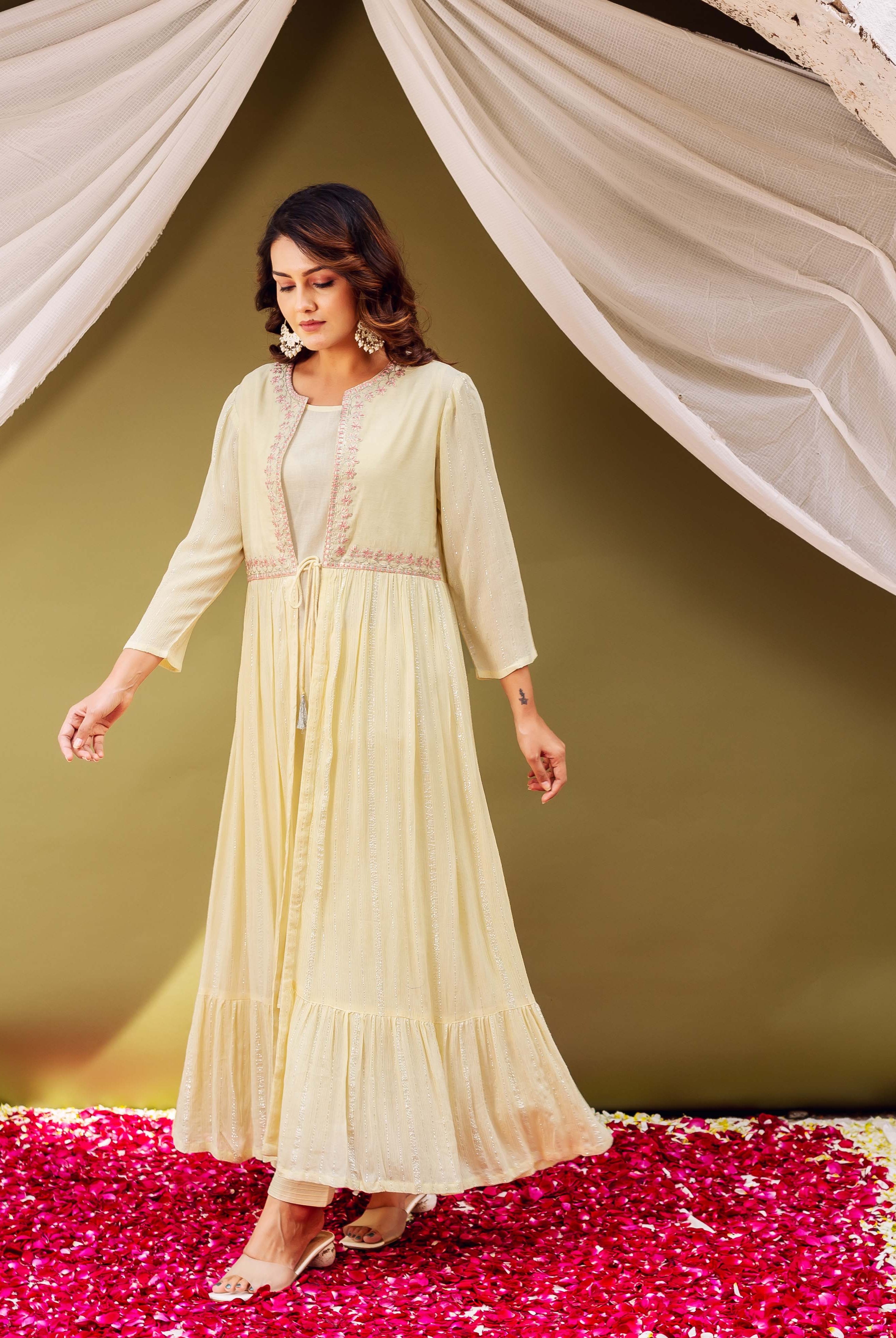 Full-length shot of a woman in a pale yellow shimmer jacket-style kurta with pink print.