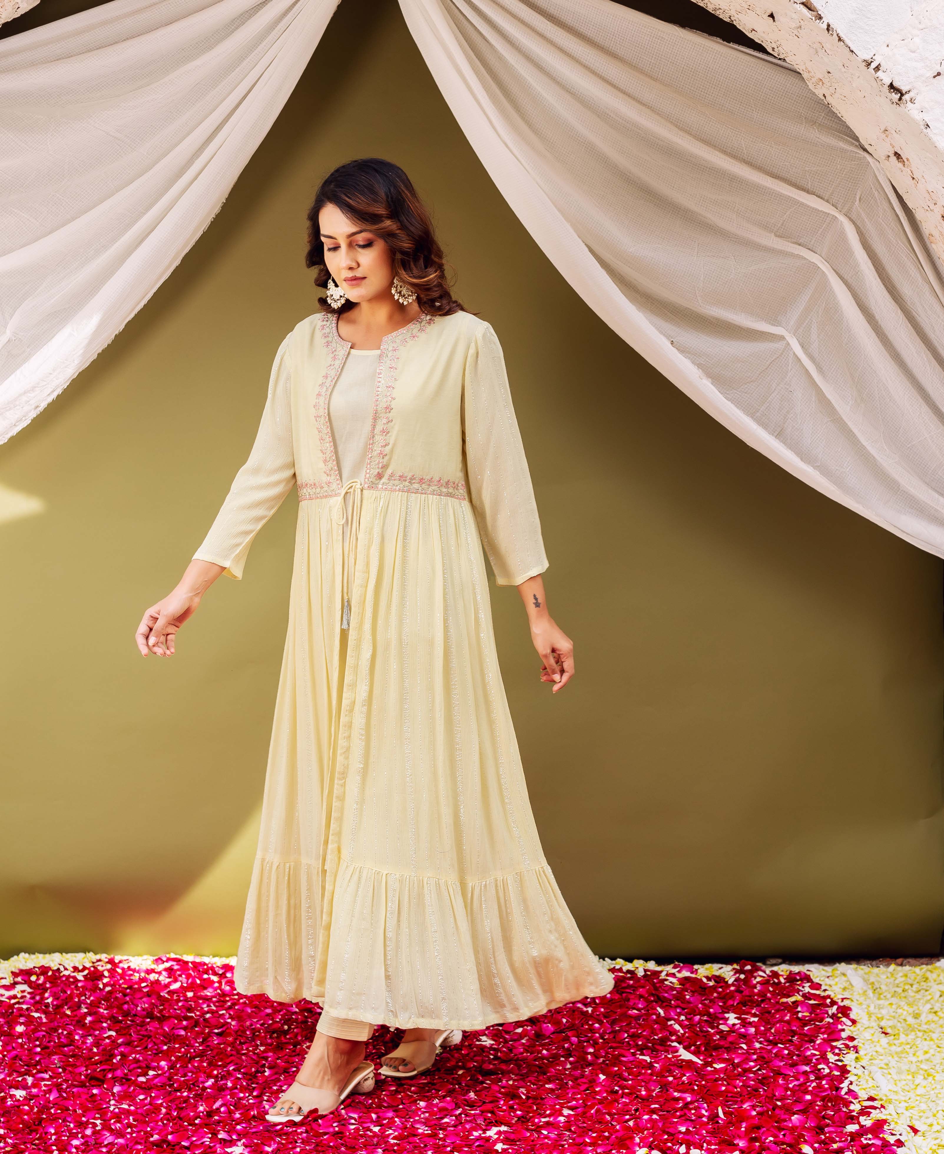 Full-length shot of a woman in a pale yellow shimmer jacket-style kurta with pink print.